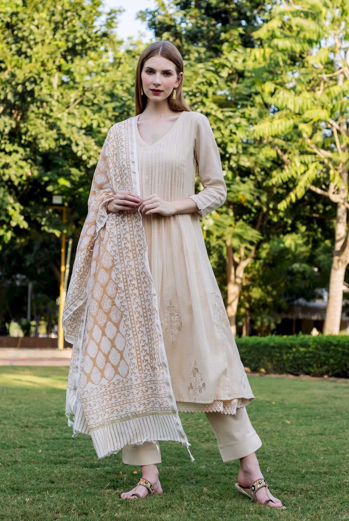 Model in a beige embroidered kurta and hand-block printed dupatta set, standing outdoors.