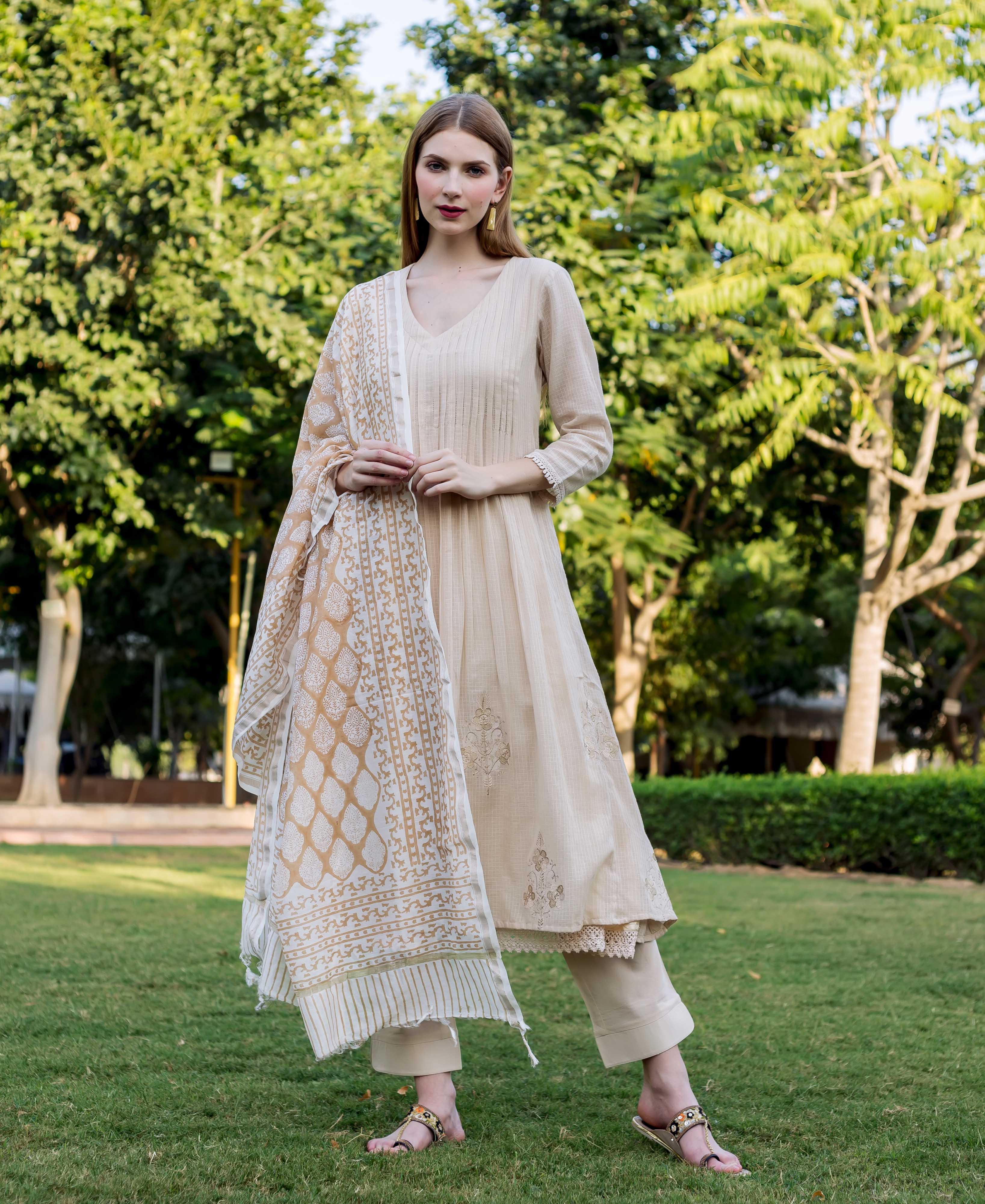 Model in a beige embroidered kurta and hand-block printed dupatta set, standing outdoors.