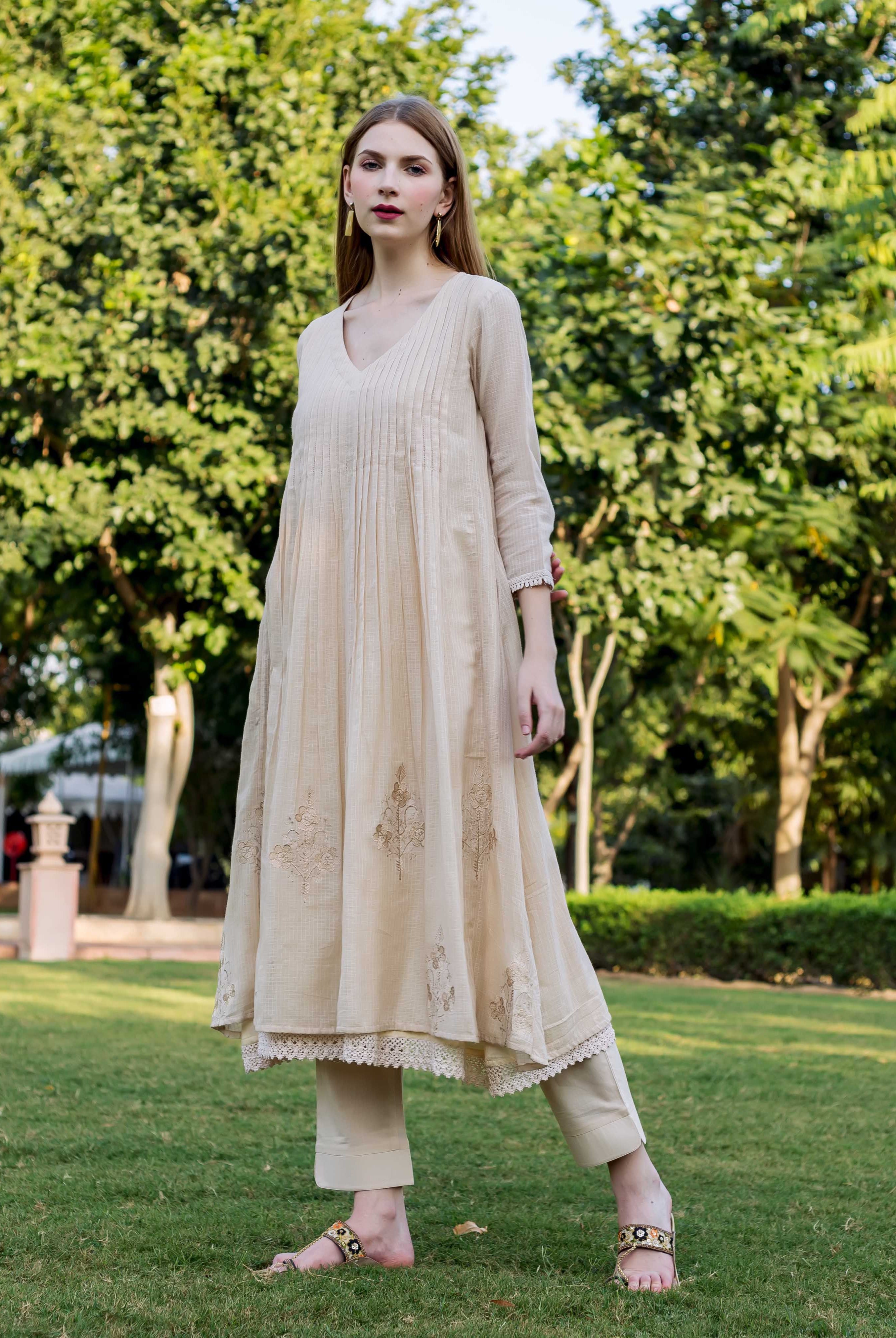 Beige embroidered Kota Doriya Kurta on model with green trees and grass background.