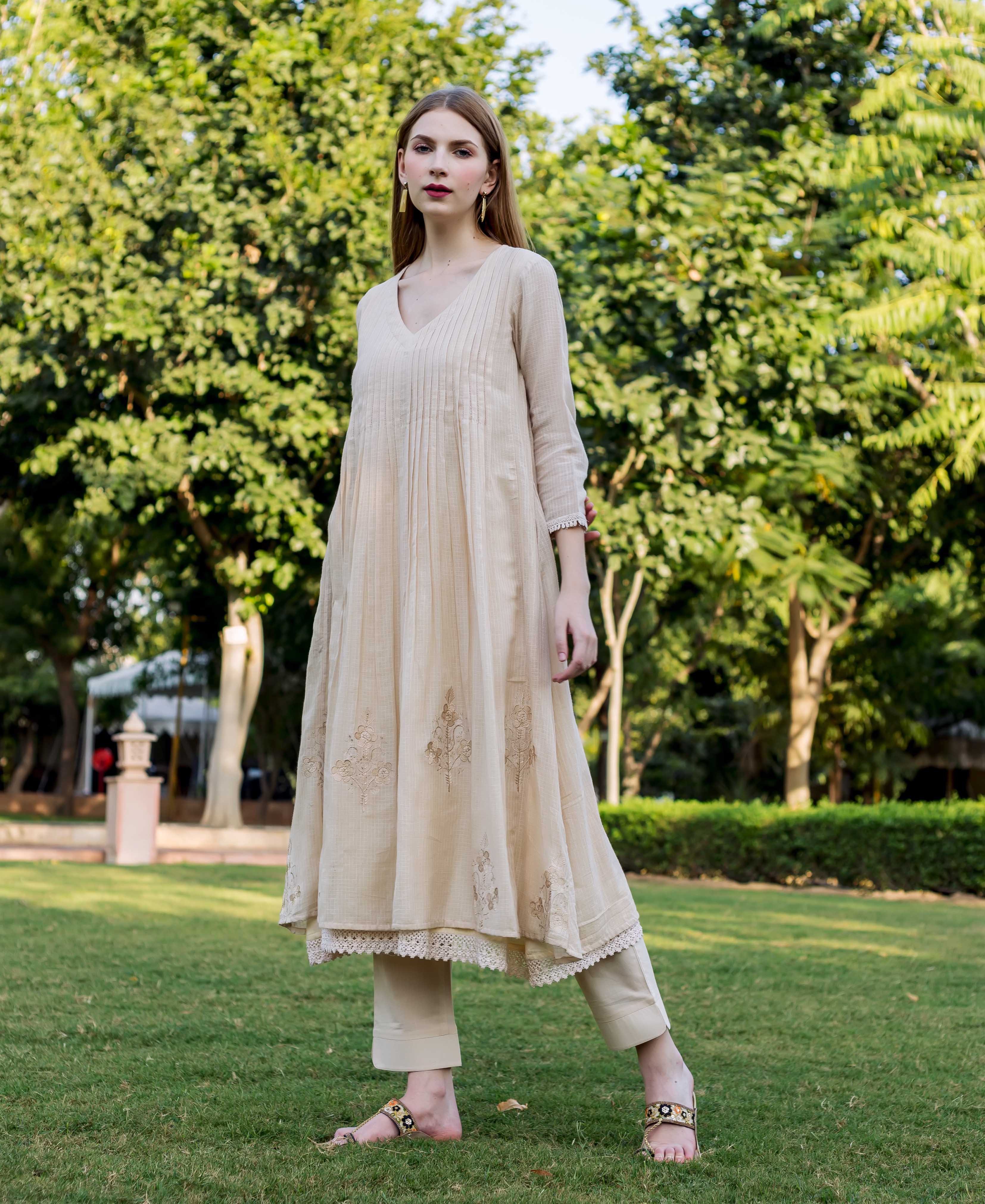 Beige embroidered Kota Doriya Kurta on model with green trees and grass background.