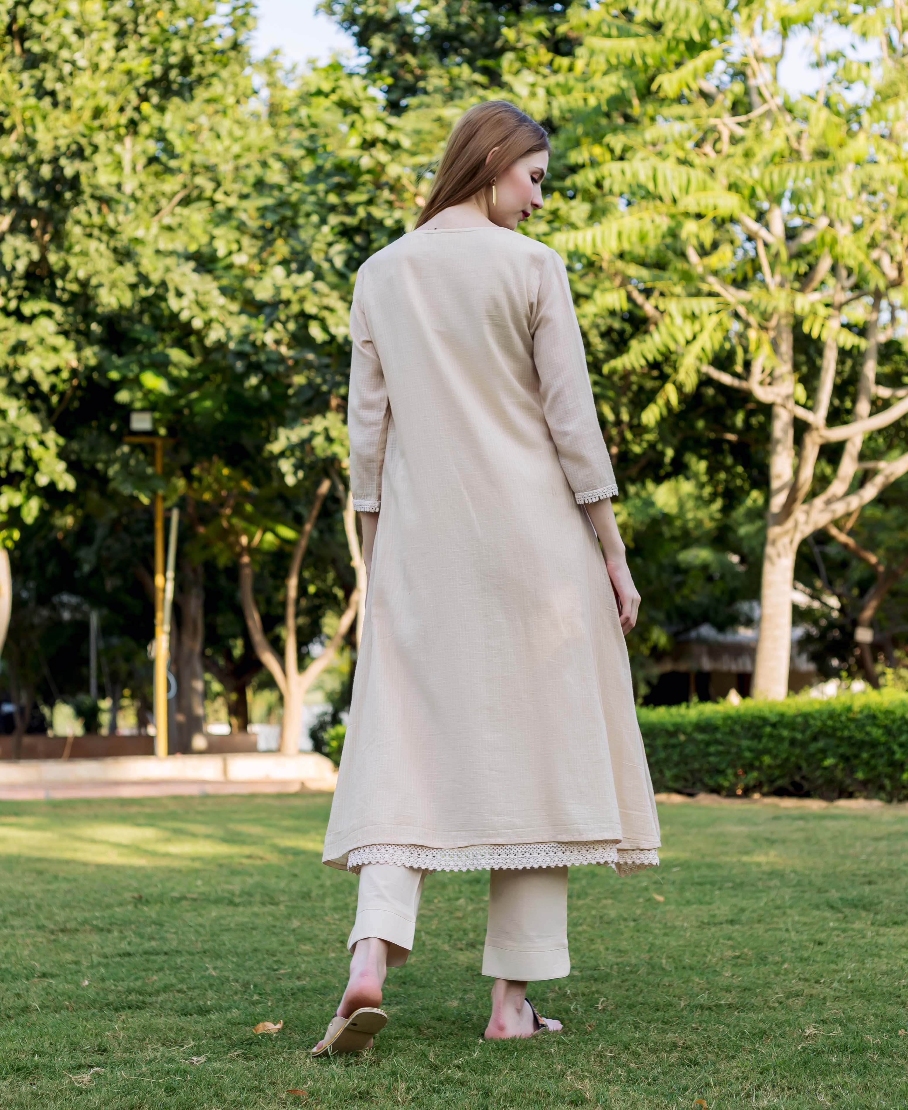 Beige embroidered kurta with delicate lace trim and pants worn by a model from back.
