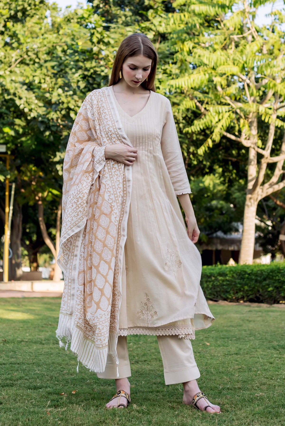 Full-length shot of woman in beige embroidered kurta set with block-printed dupatta.