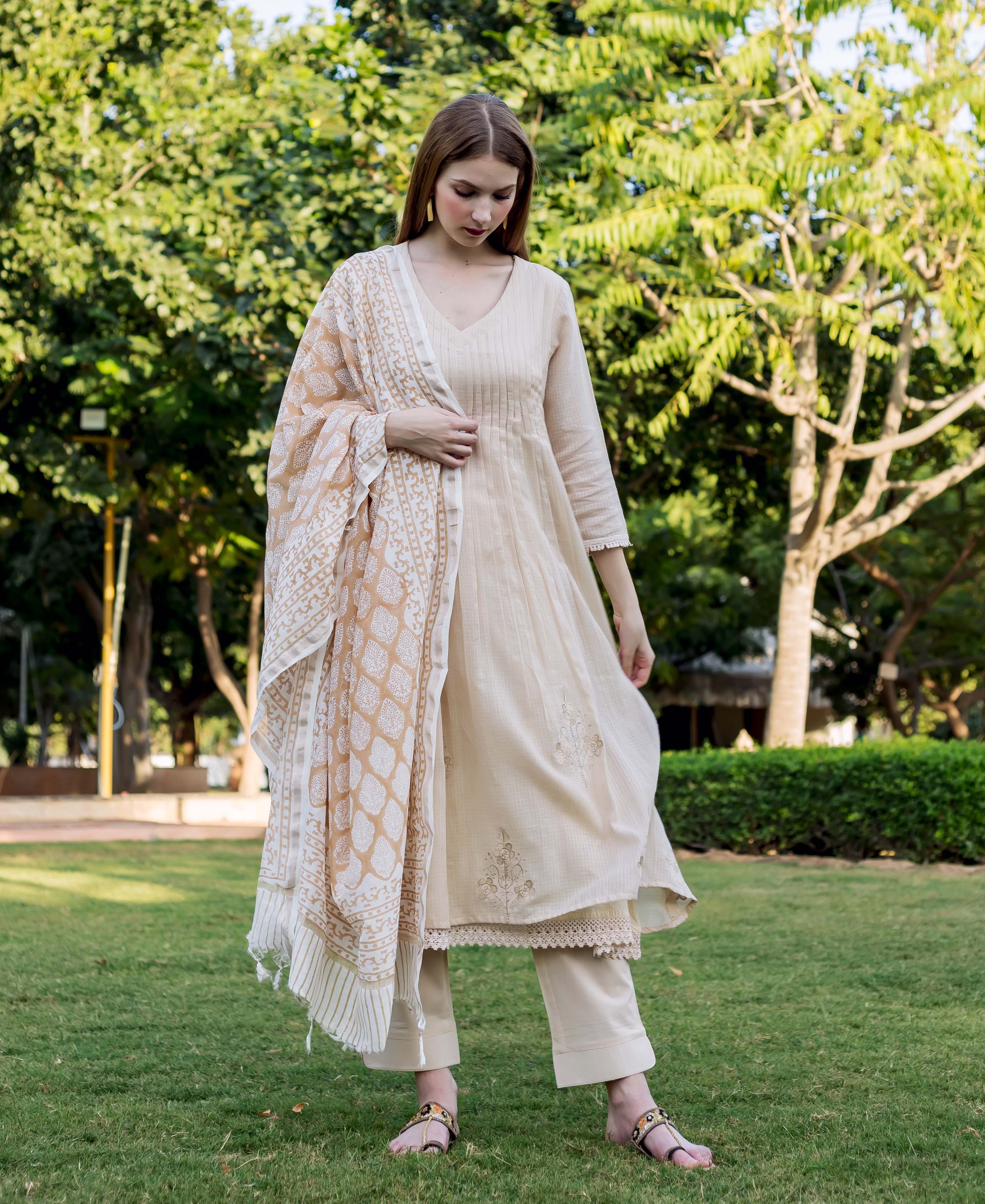 Full-length shot of woman in beige embroidered kurta set with block-printed dupatta.