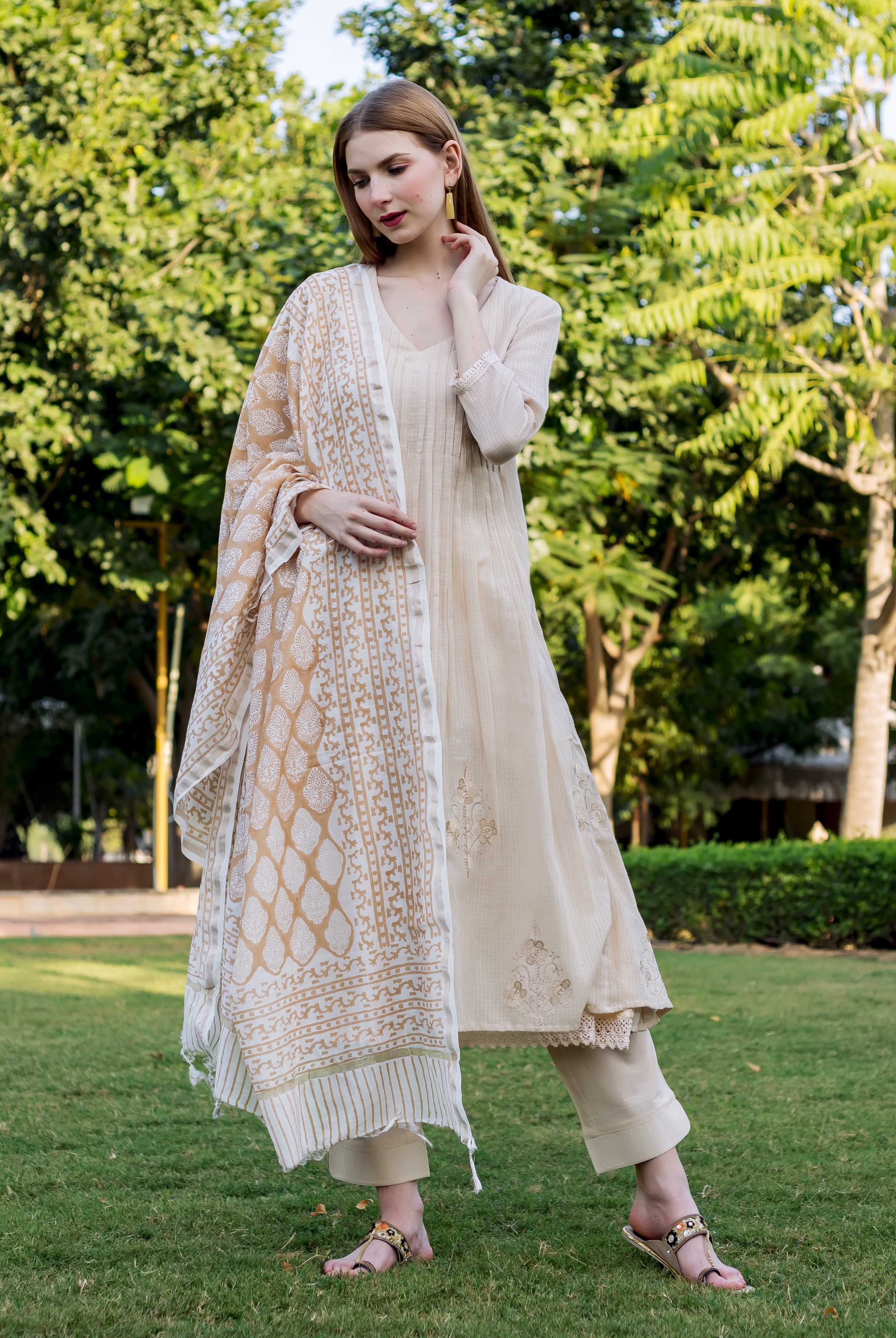 Woman models beige embroidered Kota Doriya kurta set and block-printed dupatta.