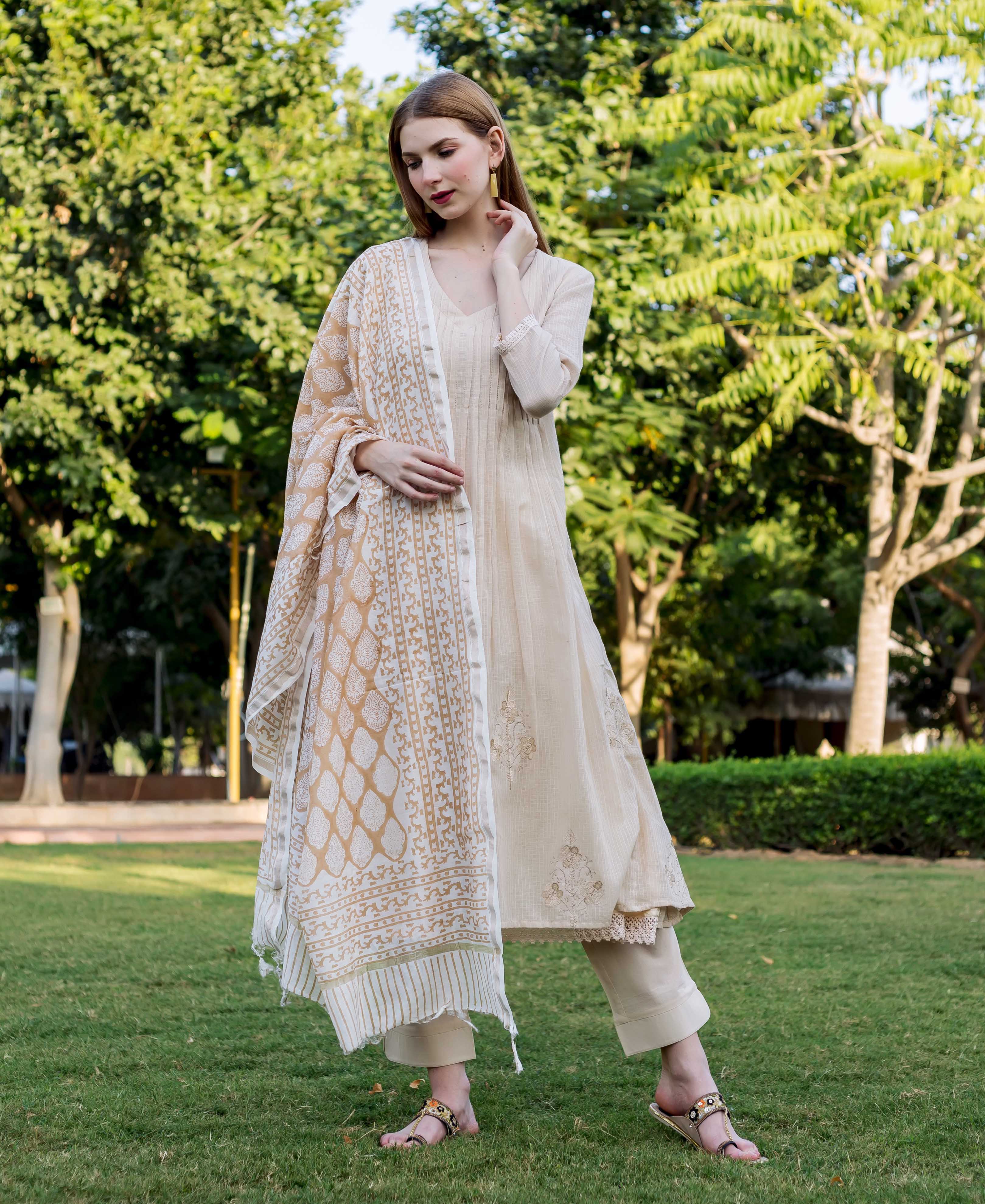 Woman models beige embroidered Kota Doriya kurta set and block-printed dupatta.