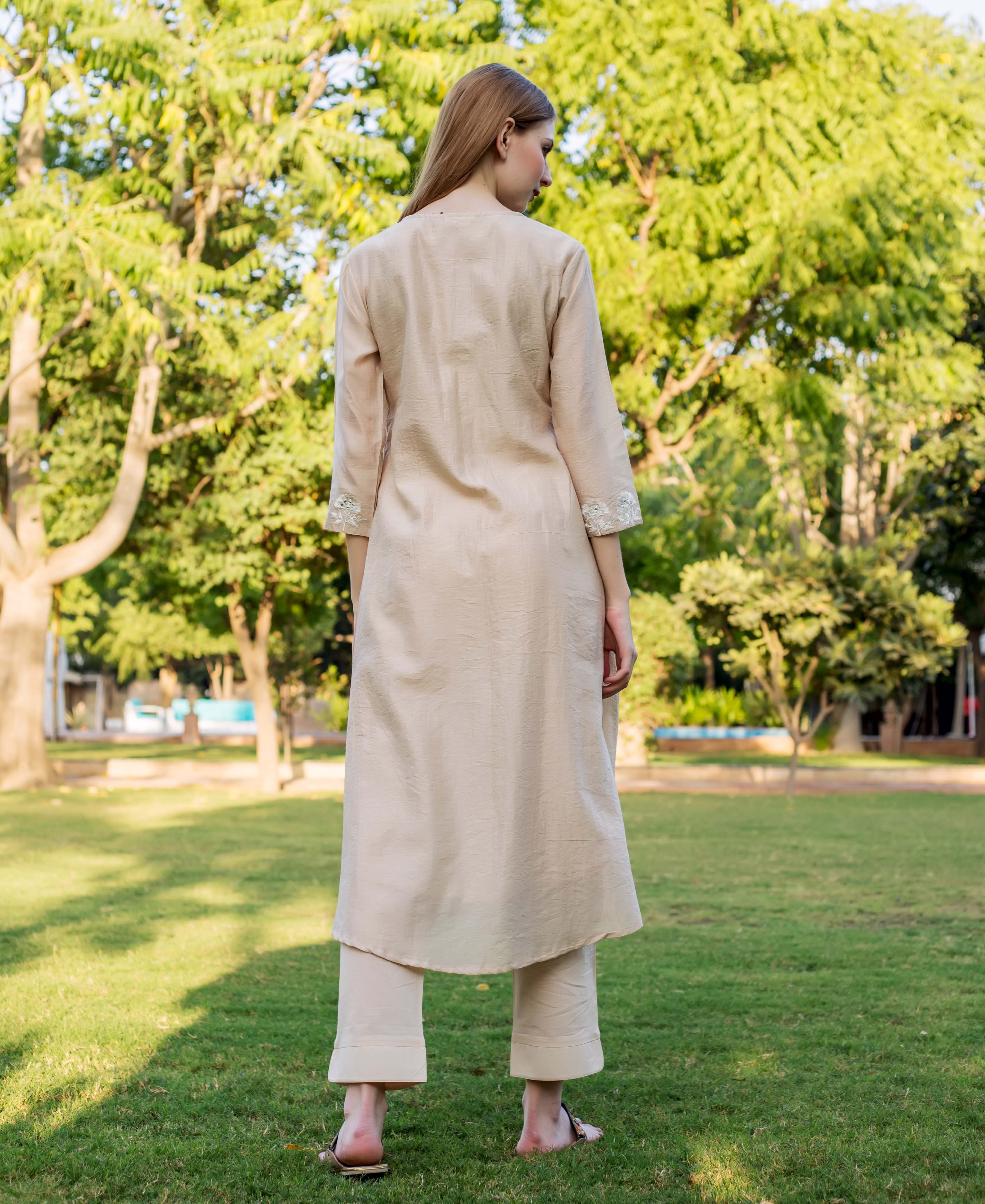 Beige chanderi embroidered kurta and pants on model standing in outdoor setting.