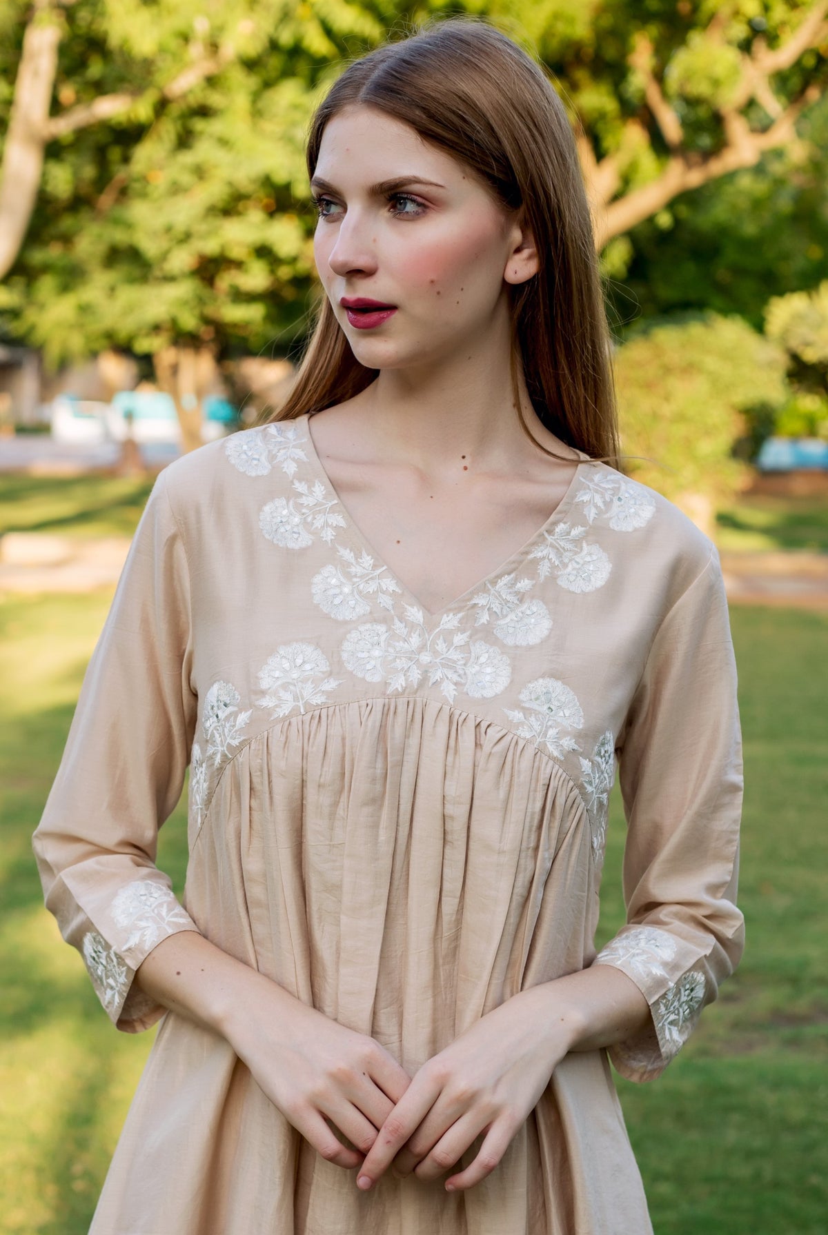A model wearing a beige kurta with white floral embroidery.