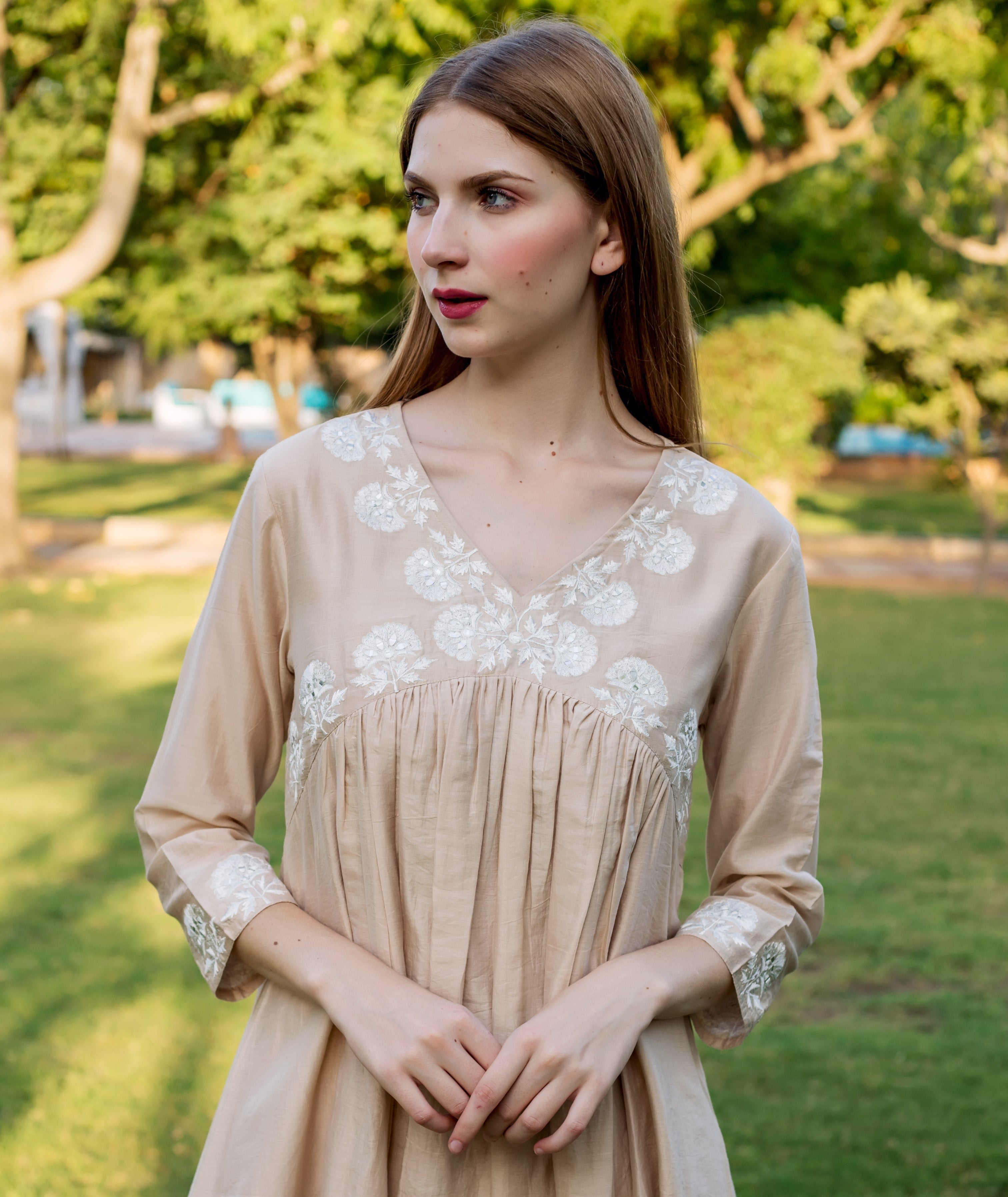 A model wearing a beige kurta with white floral embroidery.