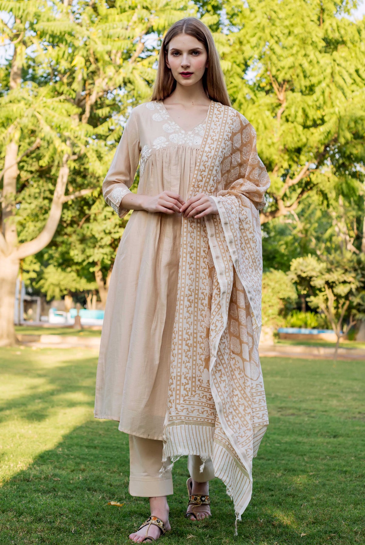 Beige chanderi embroidered kurta with white floral pattern on neck and sleeve cuffs on model.