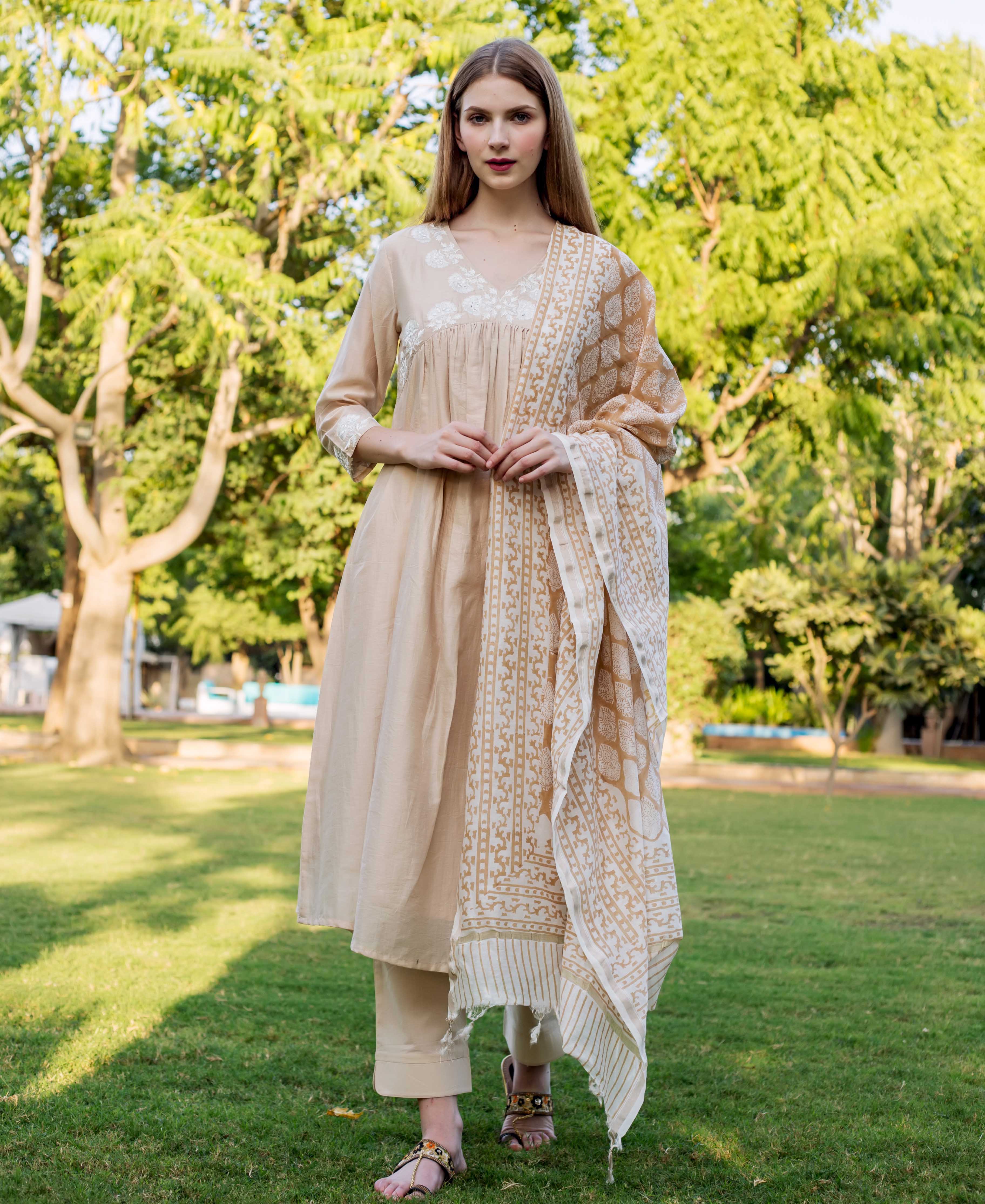 Beige chanderi embroidered kurta with white floral pattern on neck and sleeve cuffs on model.