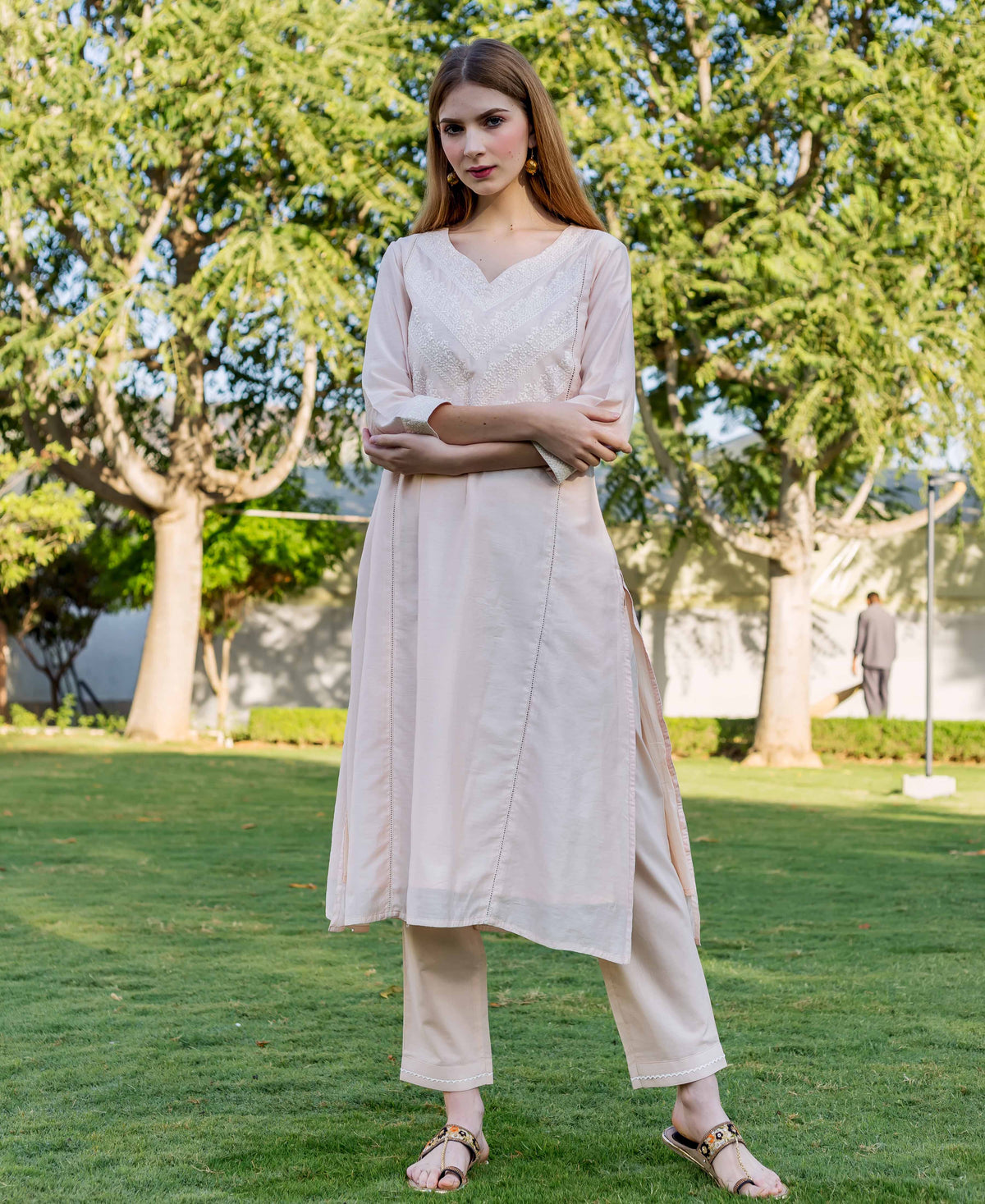 Full-length model in a baby pink embroidered kurta and matching pants.