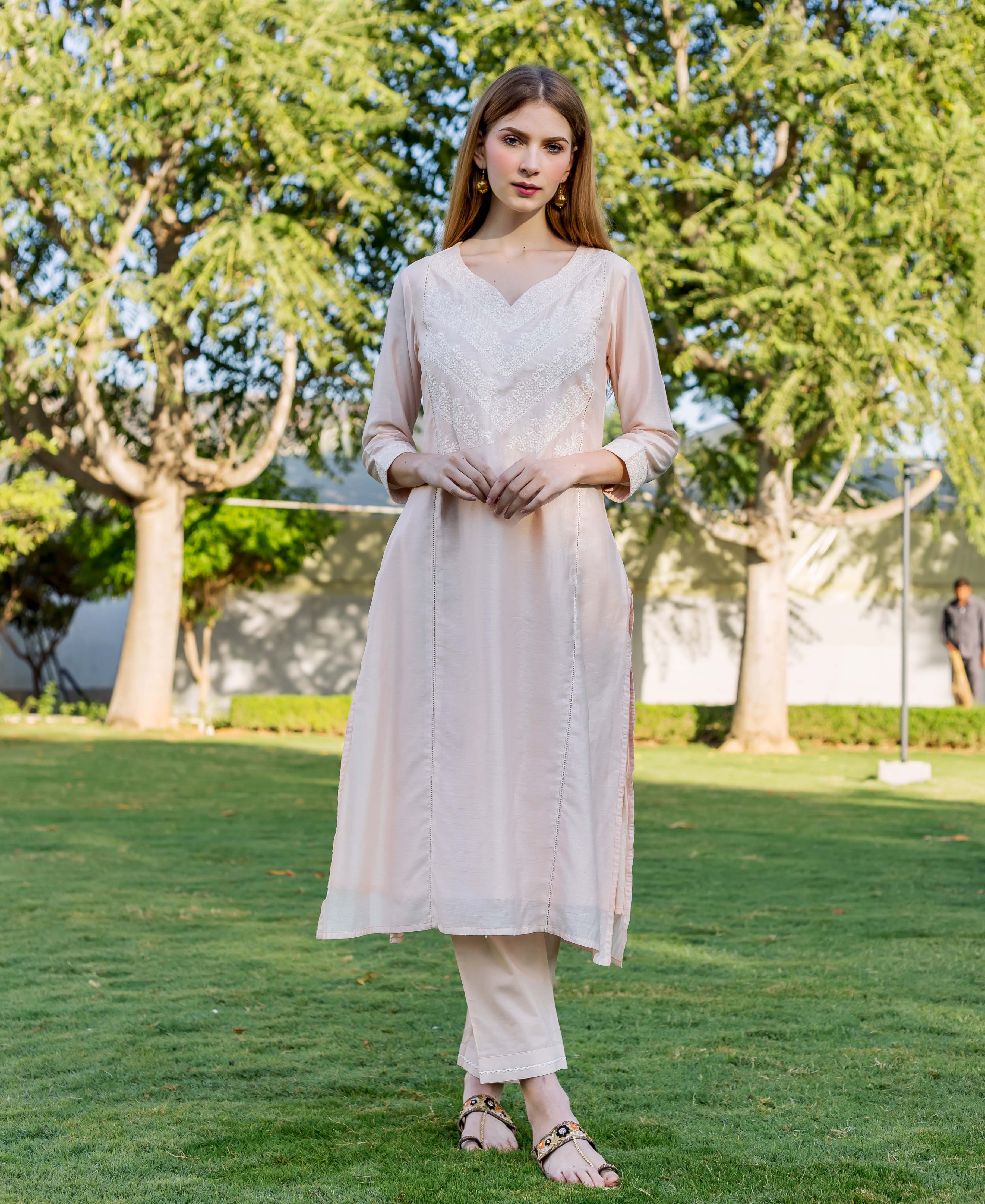 Full-length shot of a model in baby pink embroidered kurta with V-neckline.