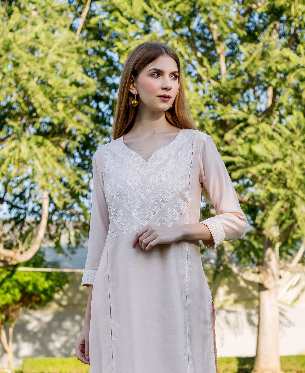Model wears a baby pink kurta with intricate white V-neck and cuff embroidery.