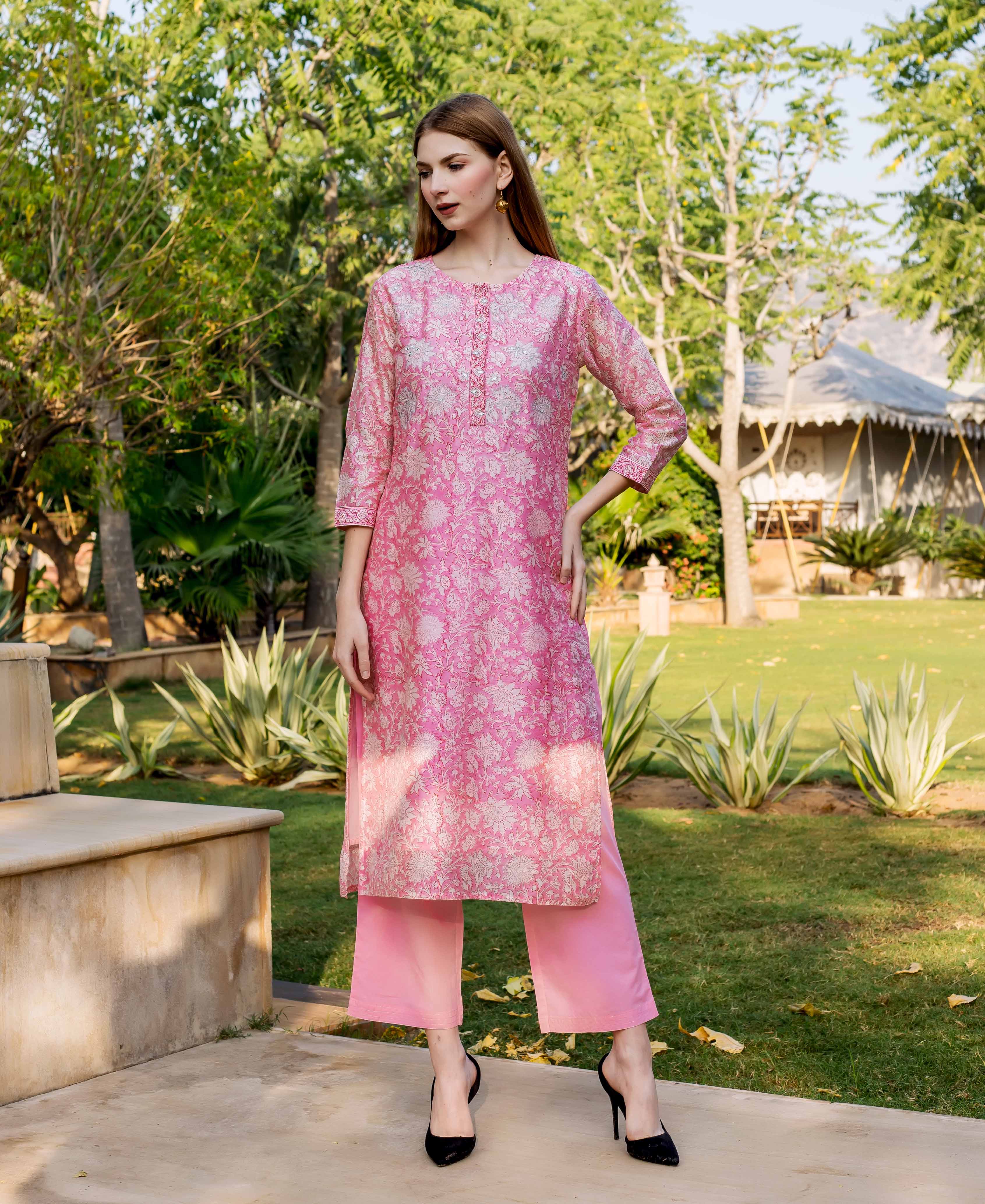 Model wears a pink hand block printed floral kurta with embroidered neckline and matching pants.