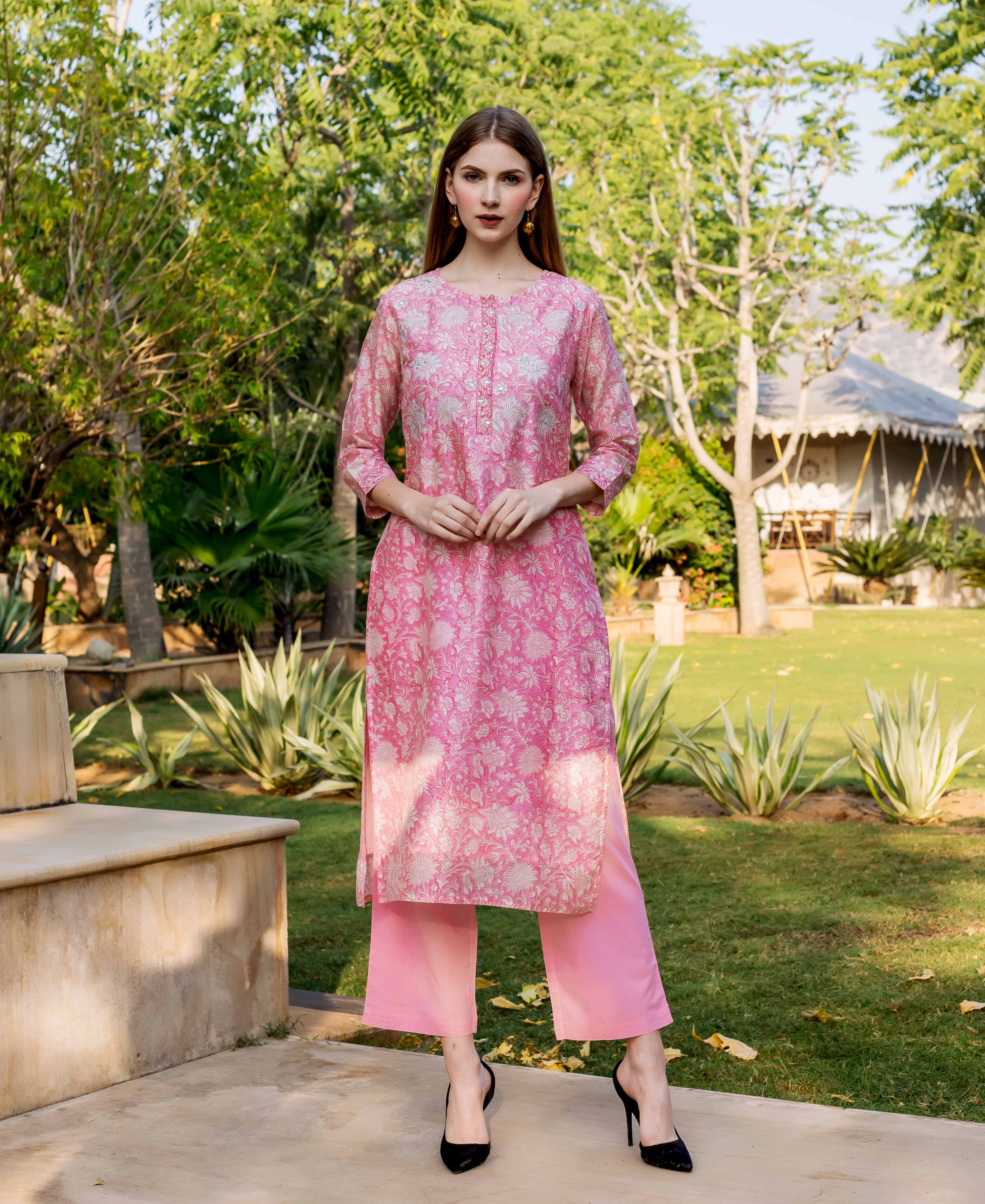 Female model in a full shot wearing a pink hand block printed and embroidered kurta and palazzo.