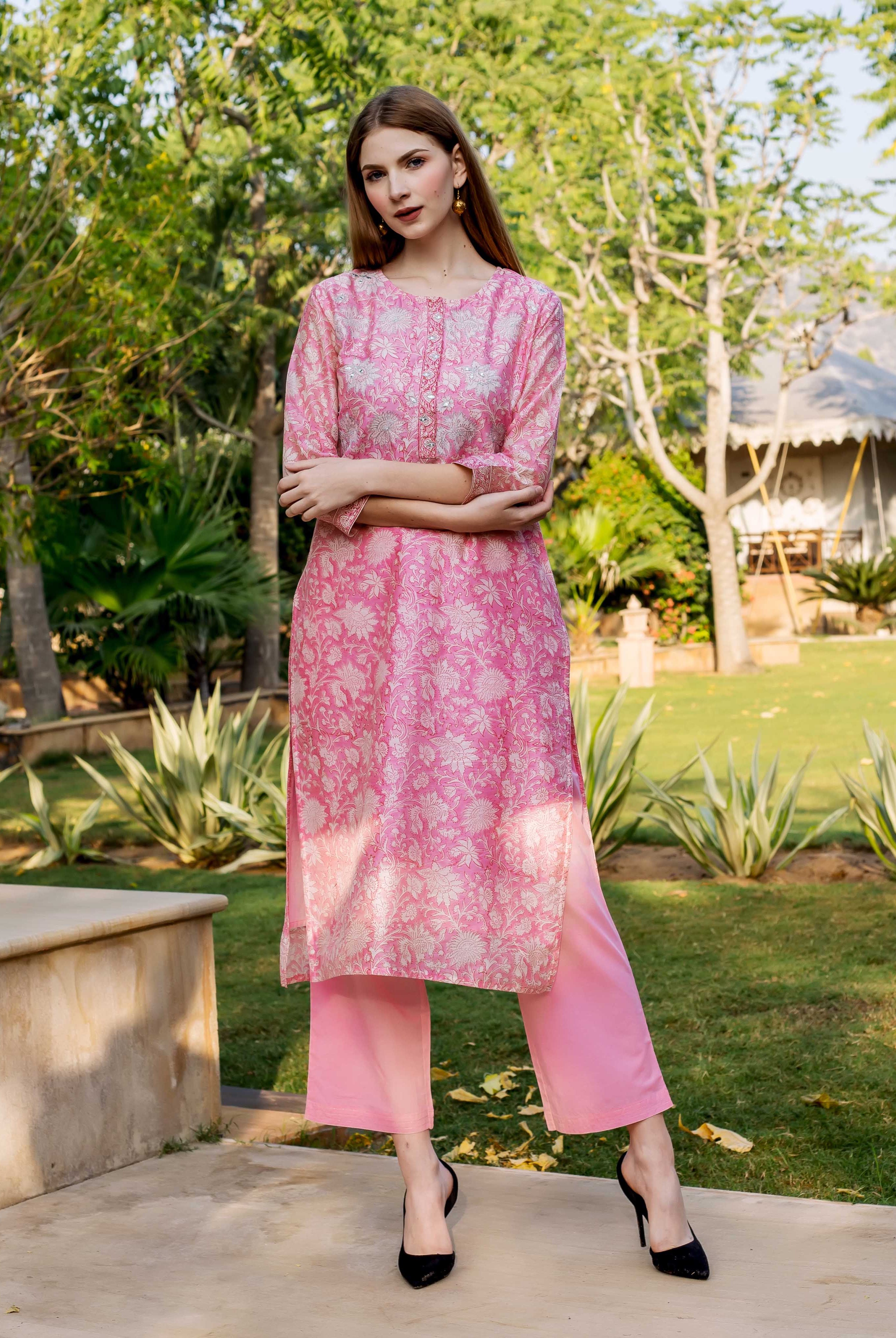 Model in pink hand block printed floral kurta with embroidery and matching pink pants.