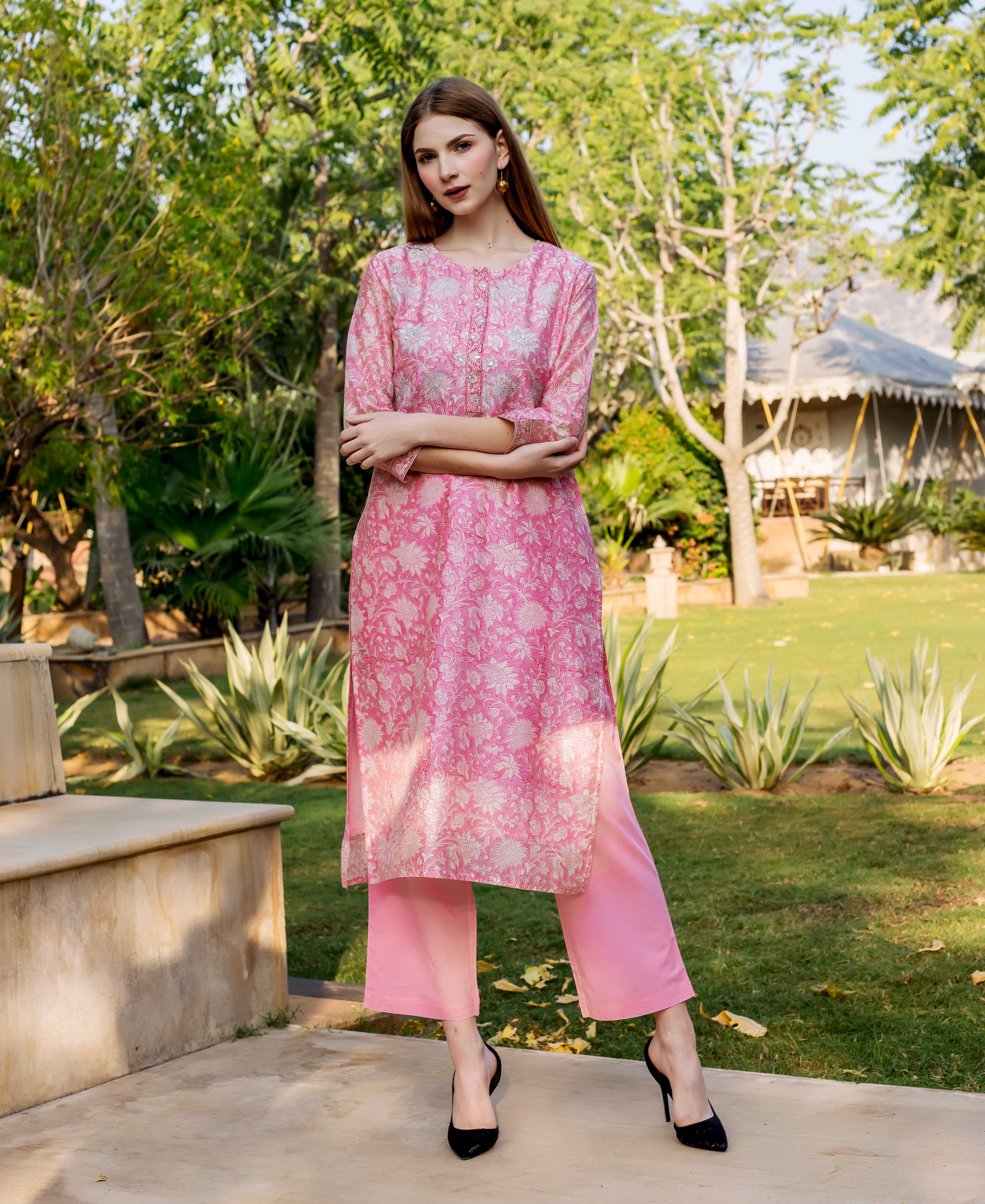 Model in pink hand block printed floral kurta with embroidery and matching pink pants.