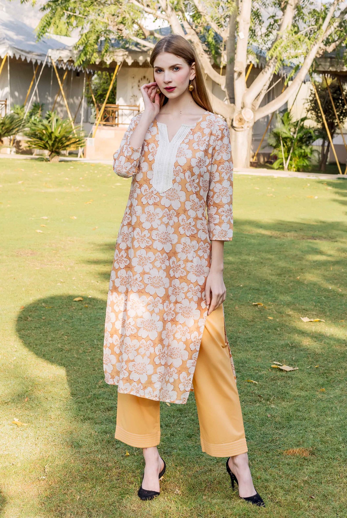 Model wearing golden yellow floral block printed kurta and trousers, front view.