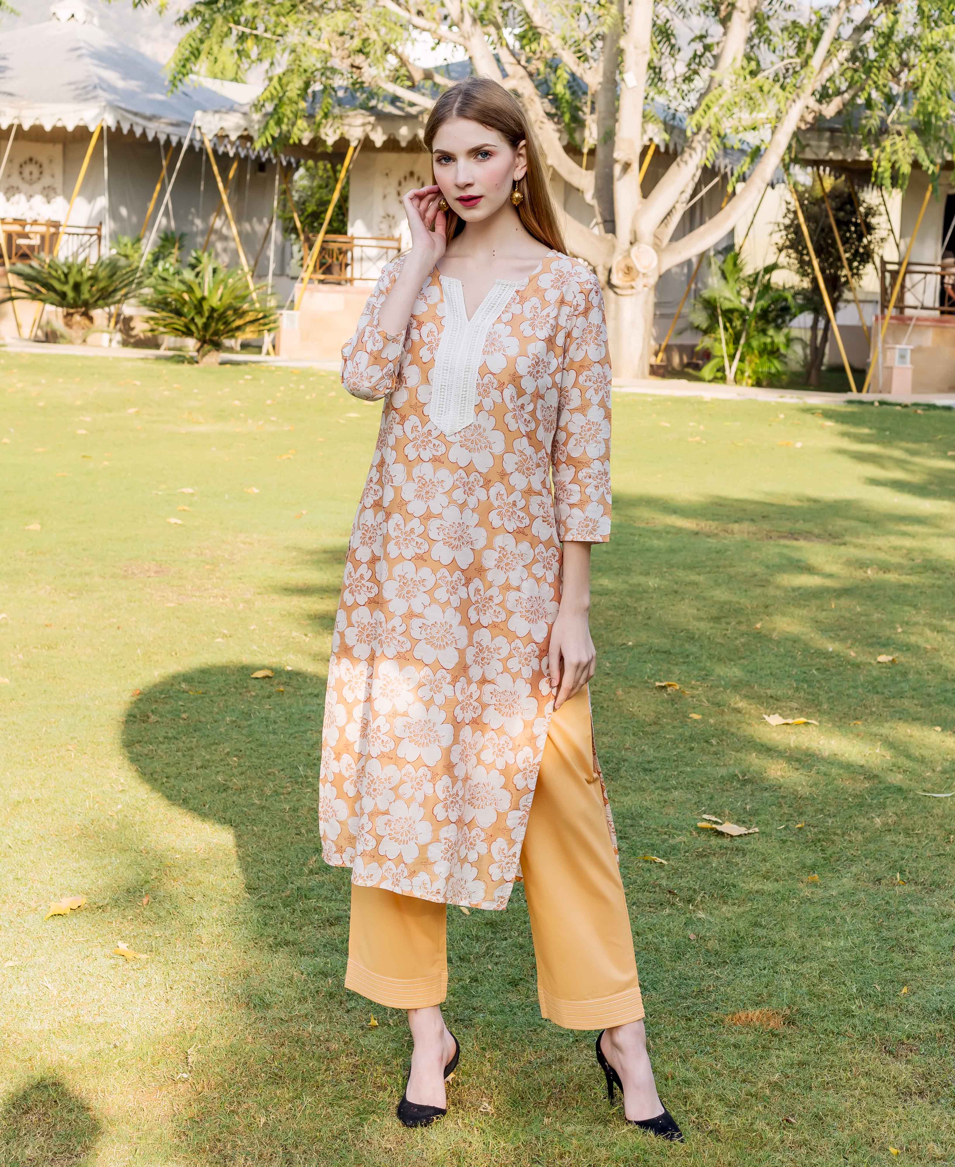Model wearing golden yellow floral block printed kurta and trousers, front view.