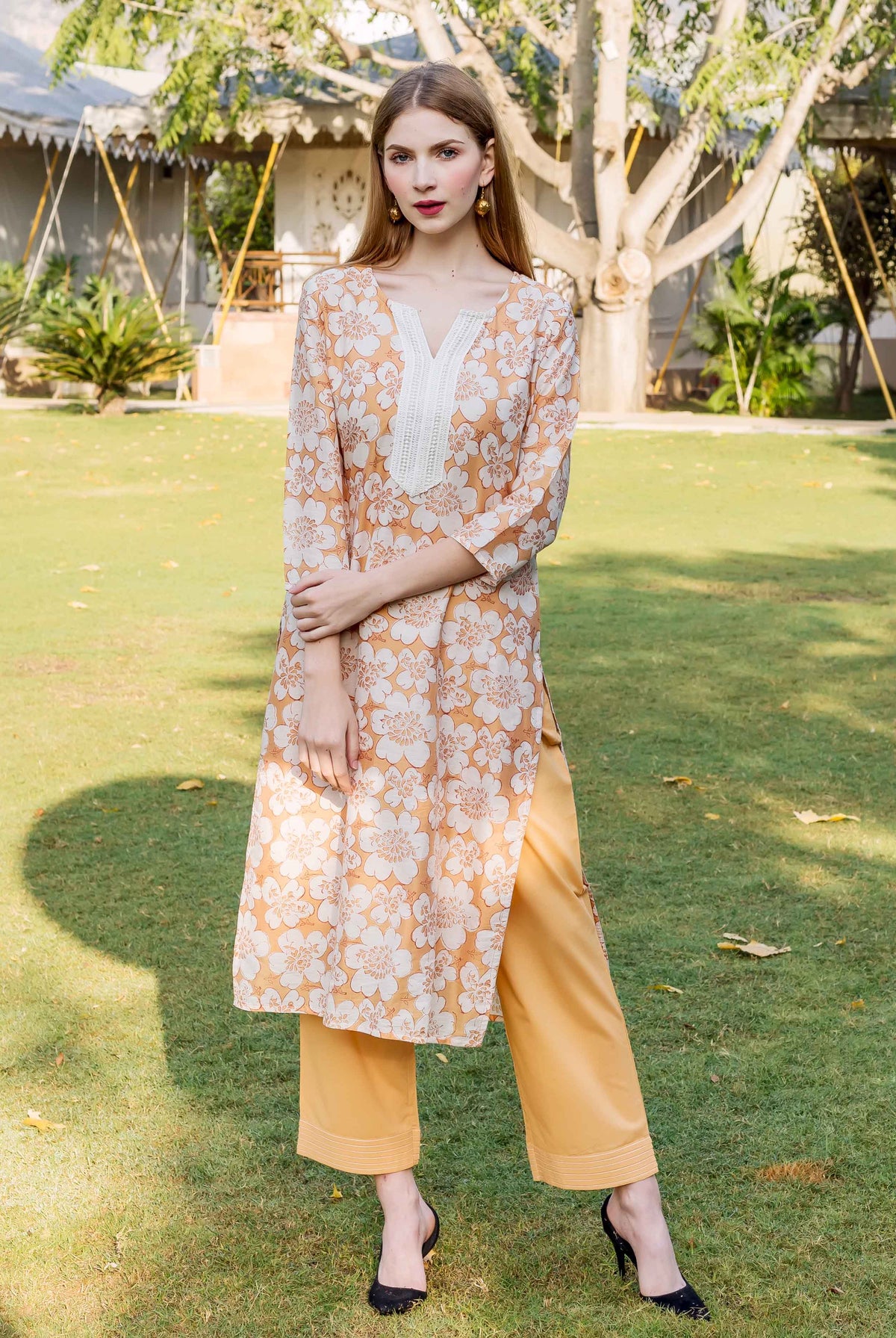 Model wearing golden yellow block printed chanderi kurta with white floral design and matching bottoms.