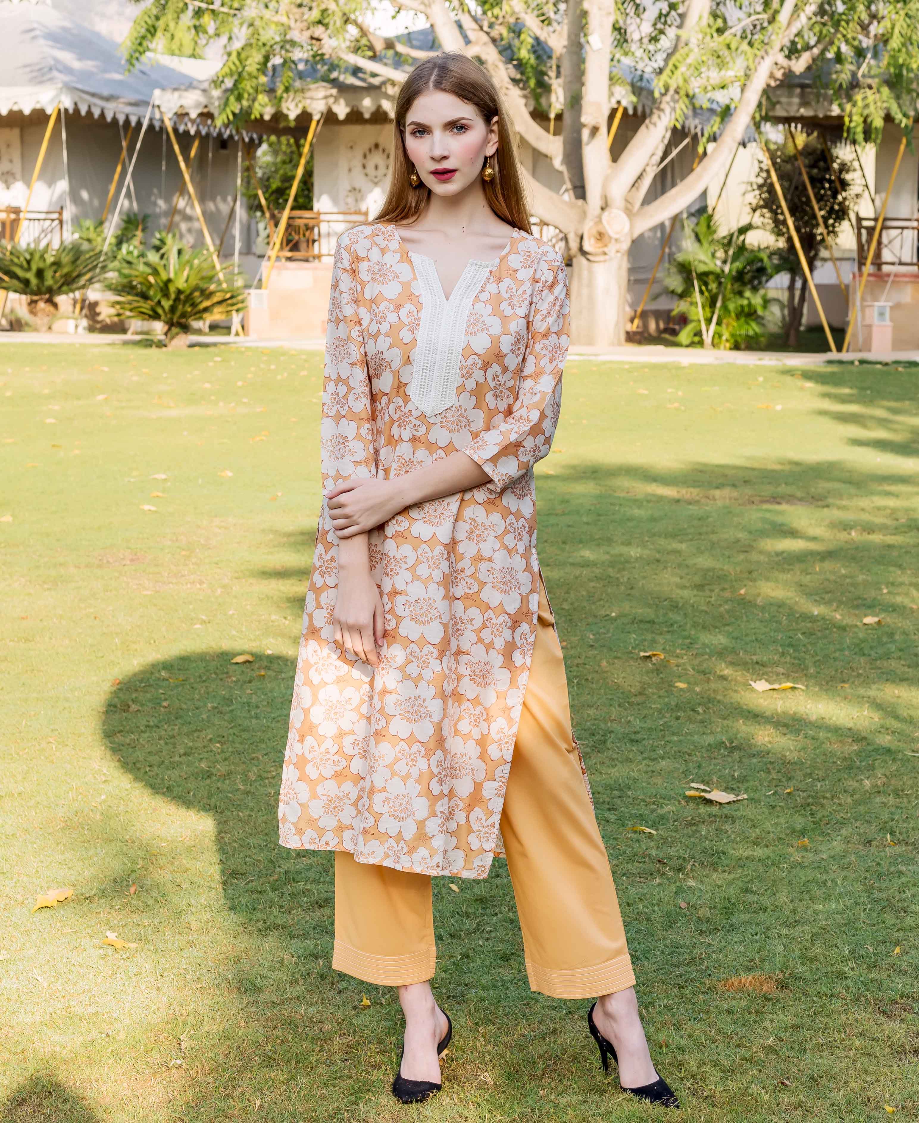 Model wearing golden yellow block printed chanderi kurta with white floral design and matching bottoms.