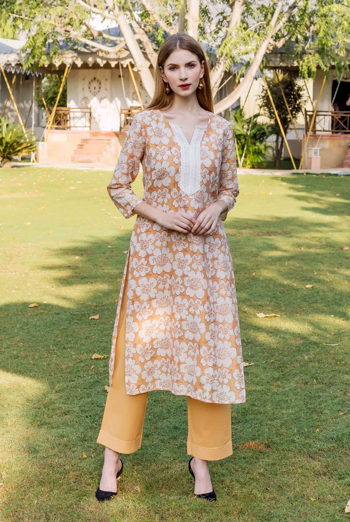 Front full look of a model in a golden yellow block printed floral kurta.