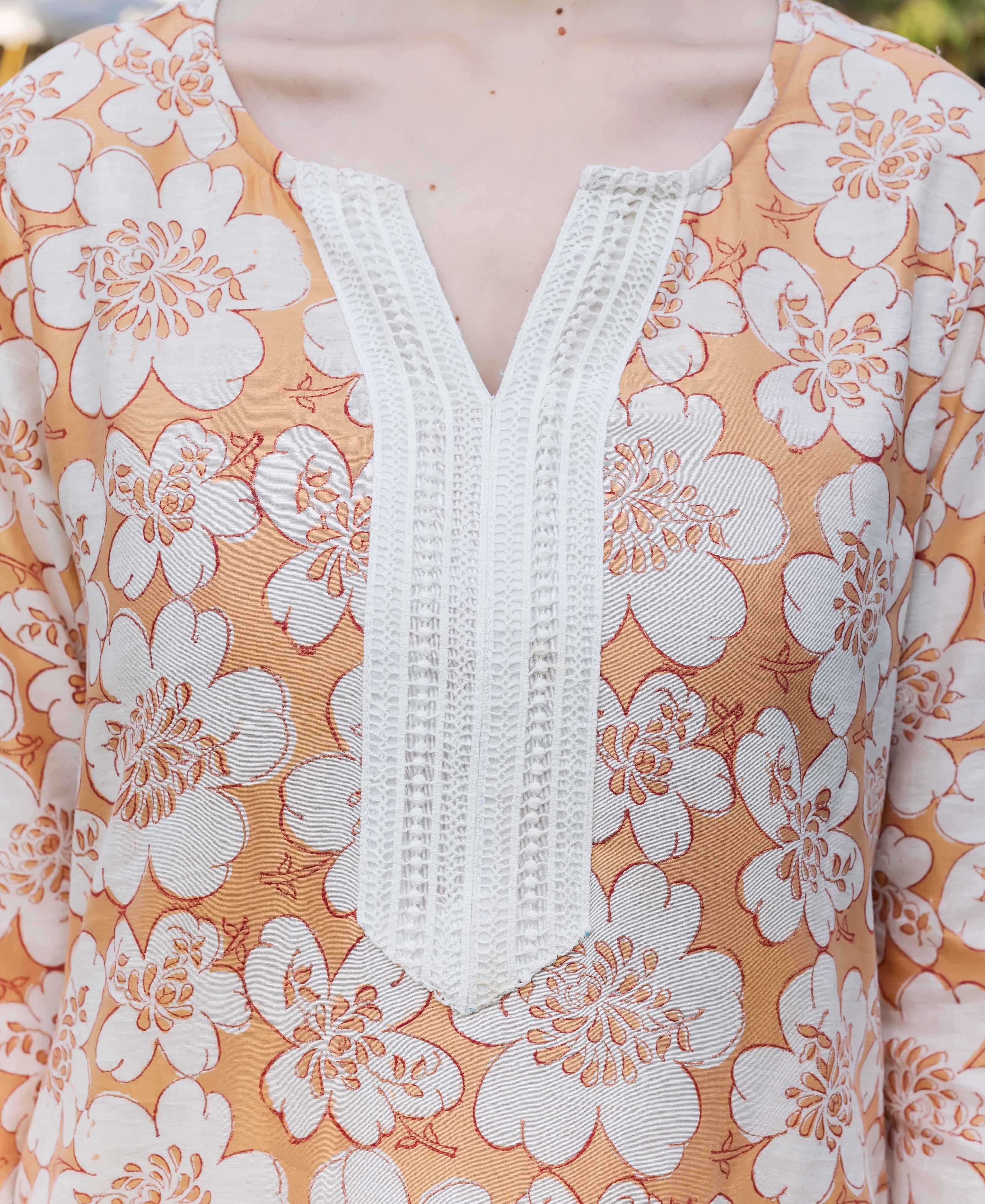 Close-up of model in golden yellow block-printed floral kurta with white lace V-neck.