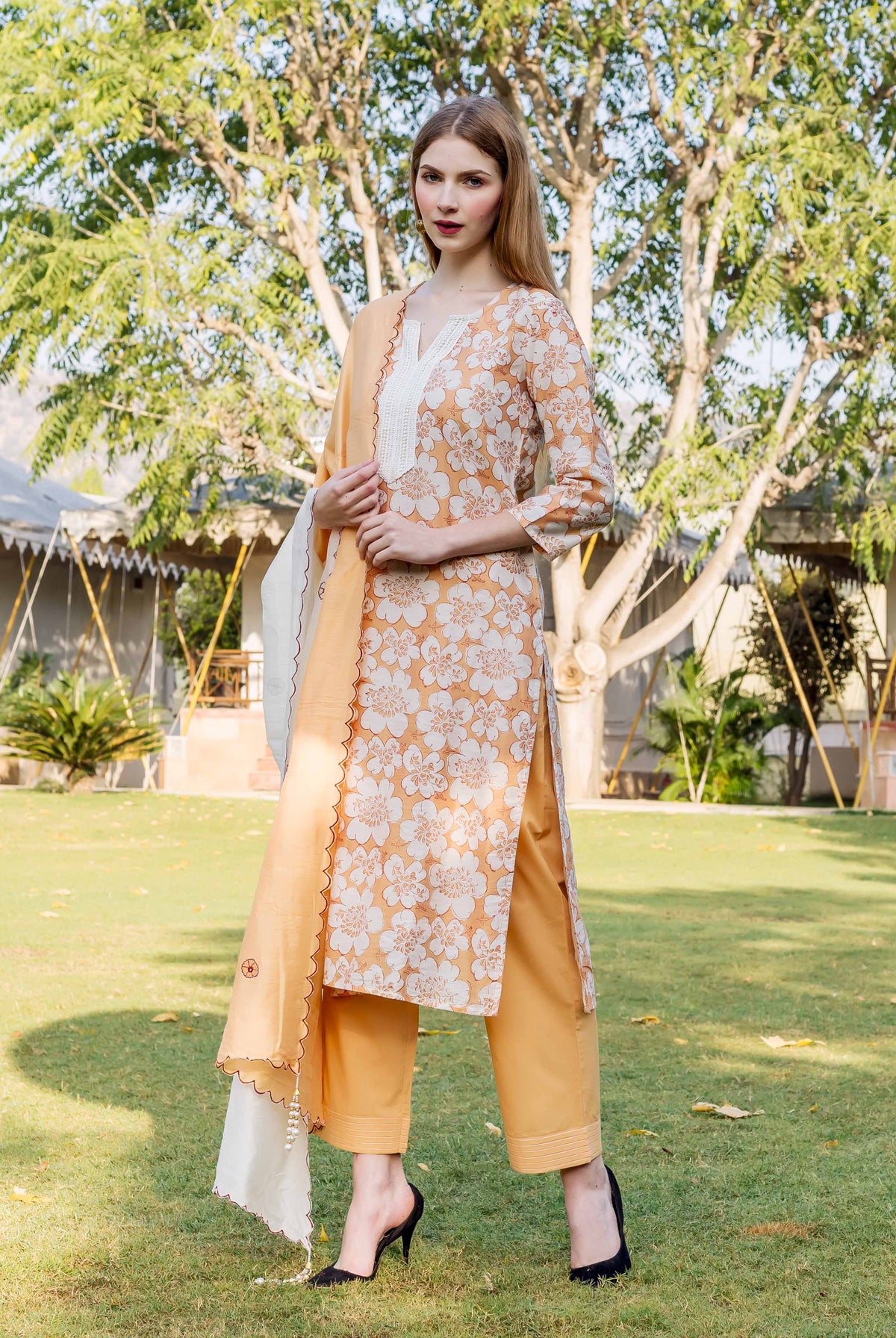 Front view of woman in golden yellow floral block printed kurta, pants, and dupatta.