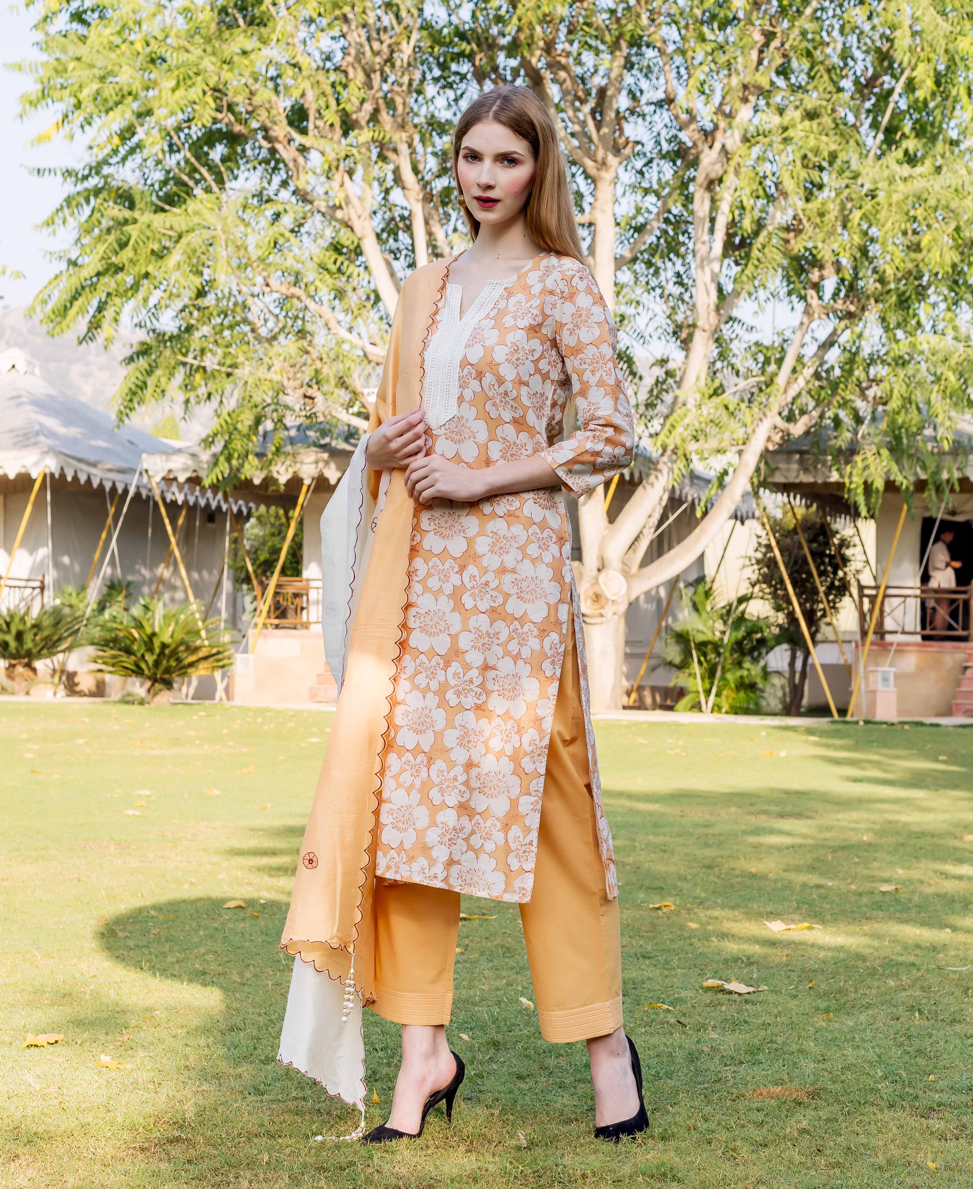 Front view of woman in golden yellow floral block printed kurta, pants, and dupatta.