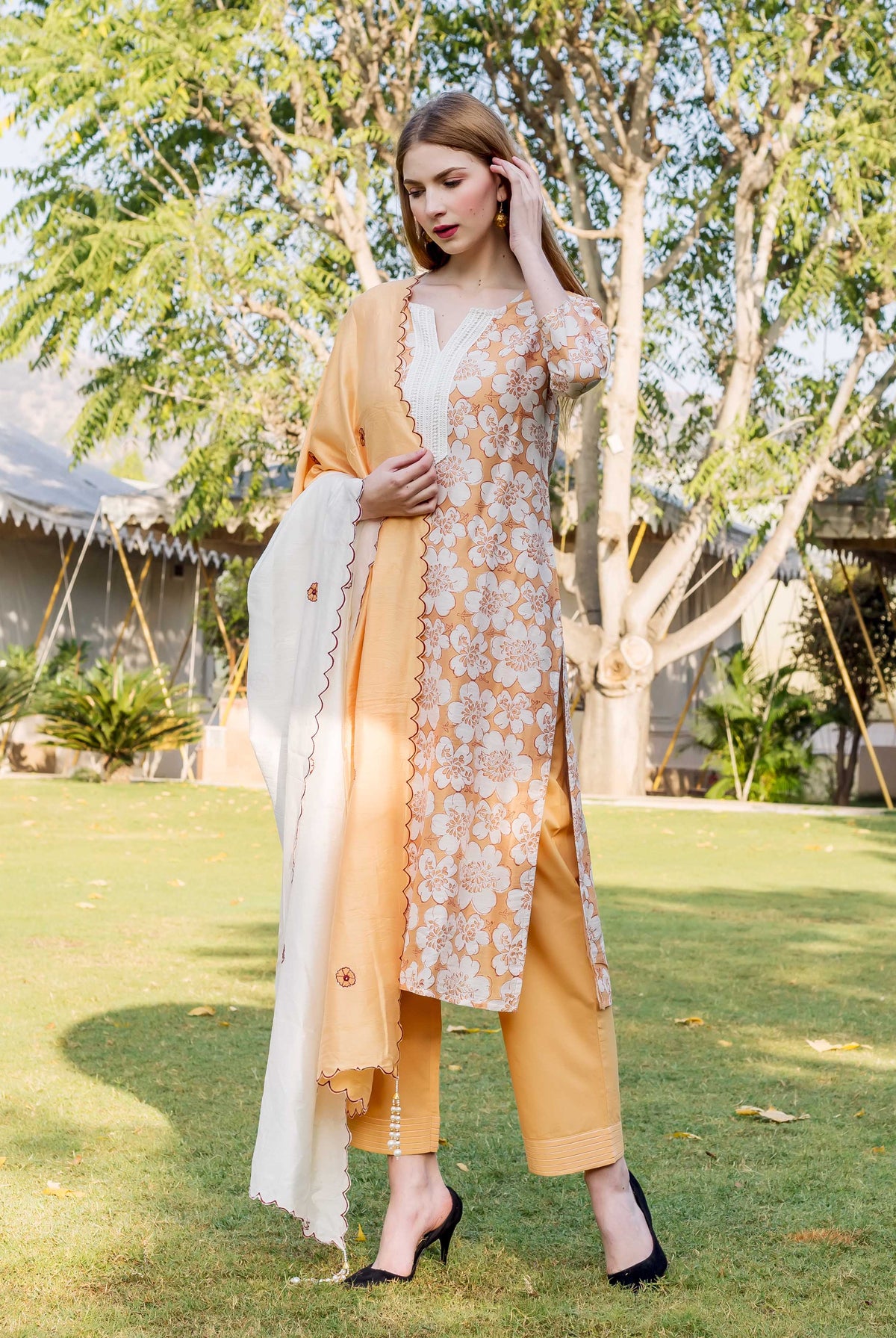 Model in full look, golden yellow floral block printed kurta set with white dupatta.