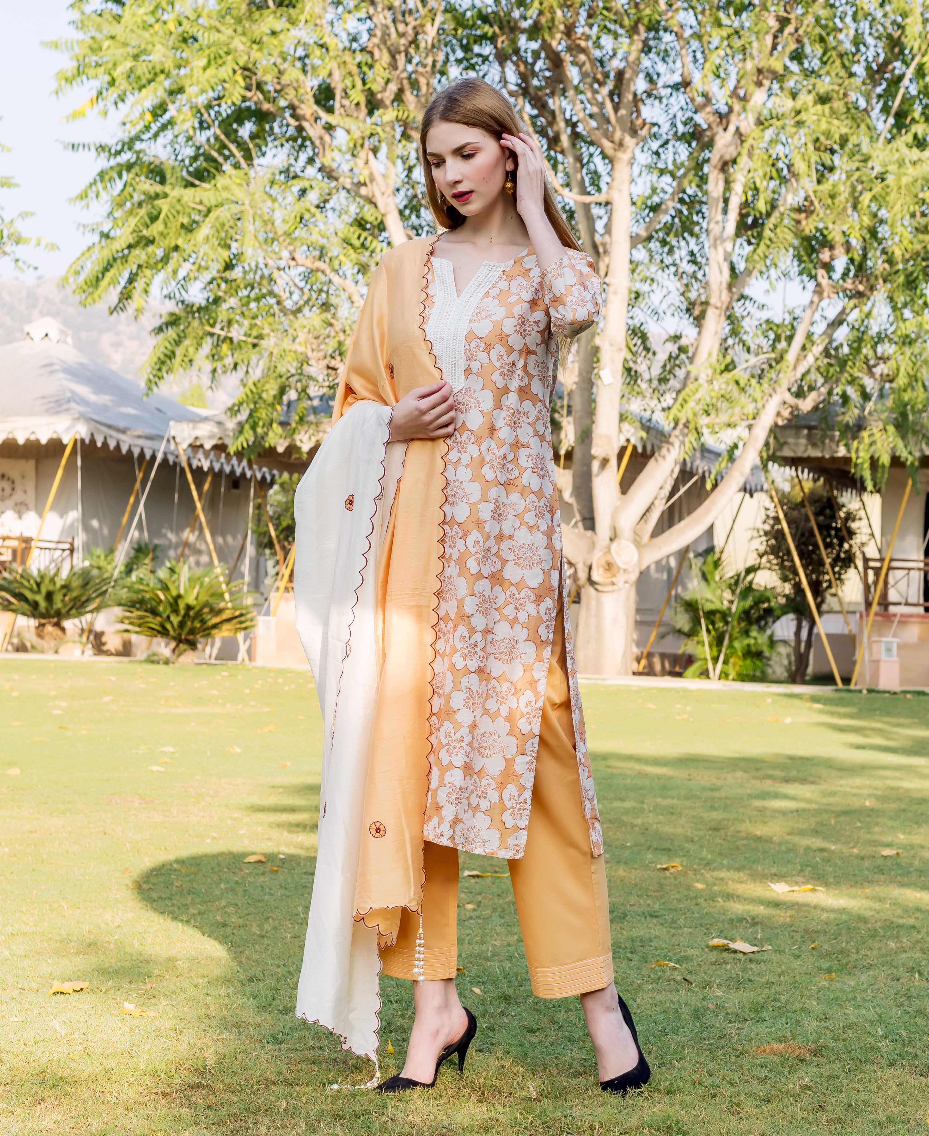 Model in full look, golden yellow floral block printed kurta set with white dupatta.