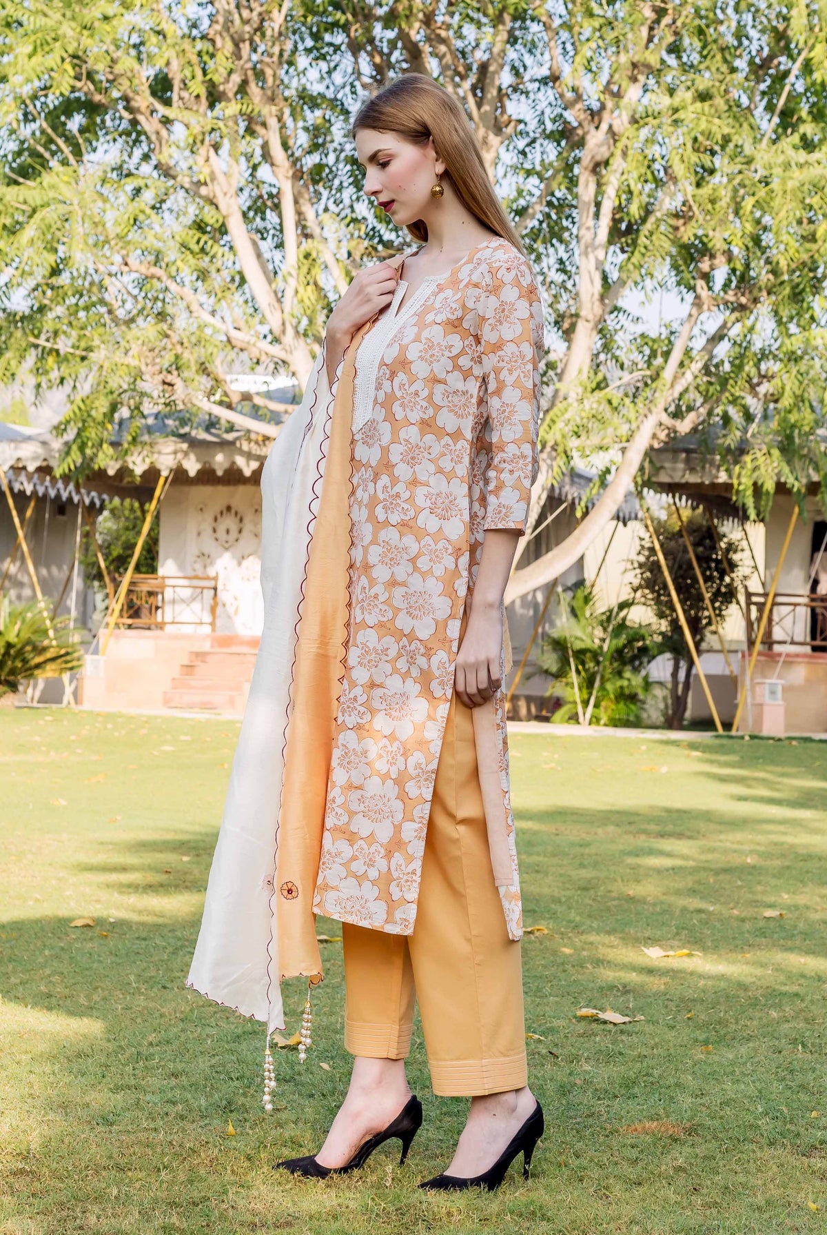 Orange and white floral patterned long tunic, mustard pants, and white scarf on a model outdoors.