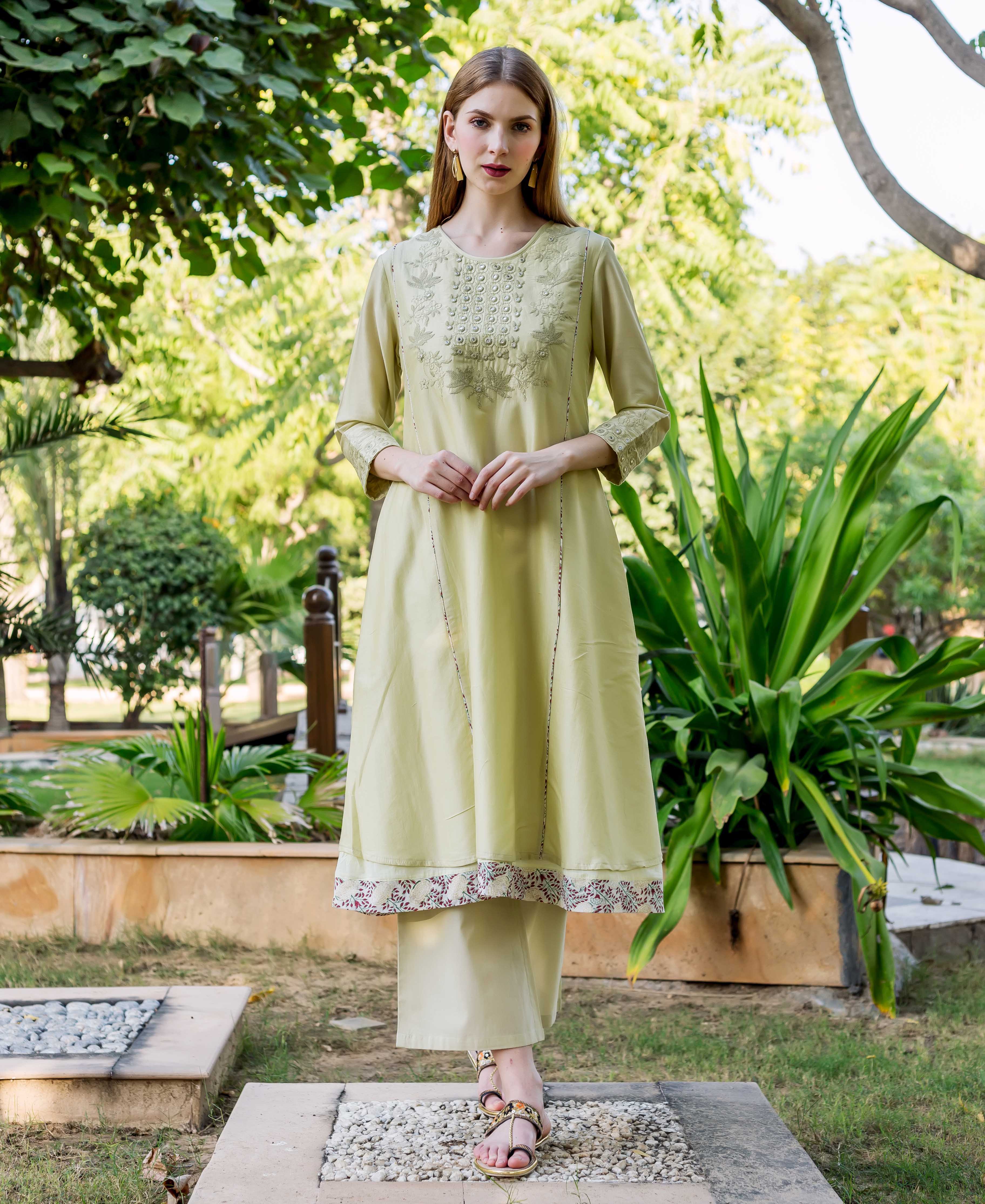 Full-length model in a sea green embroidered A-line kurta with block-printed hem.