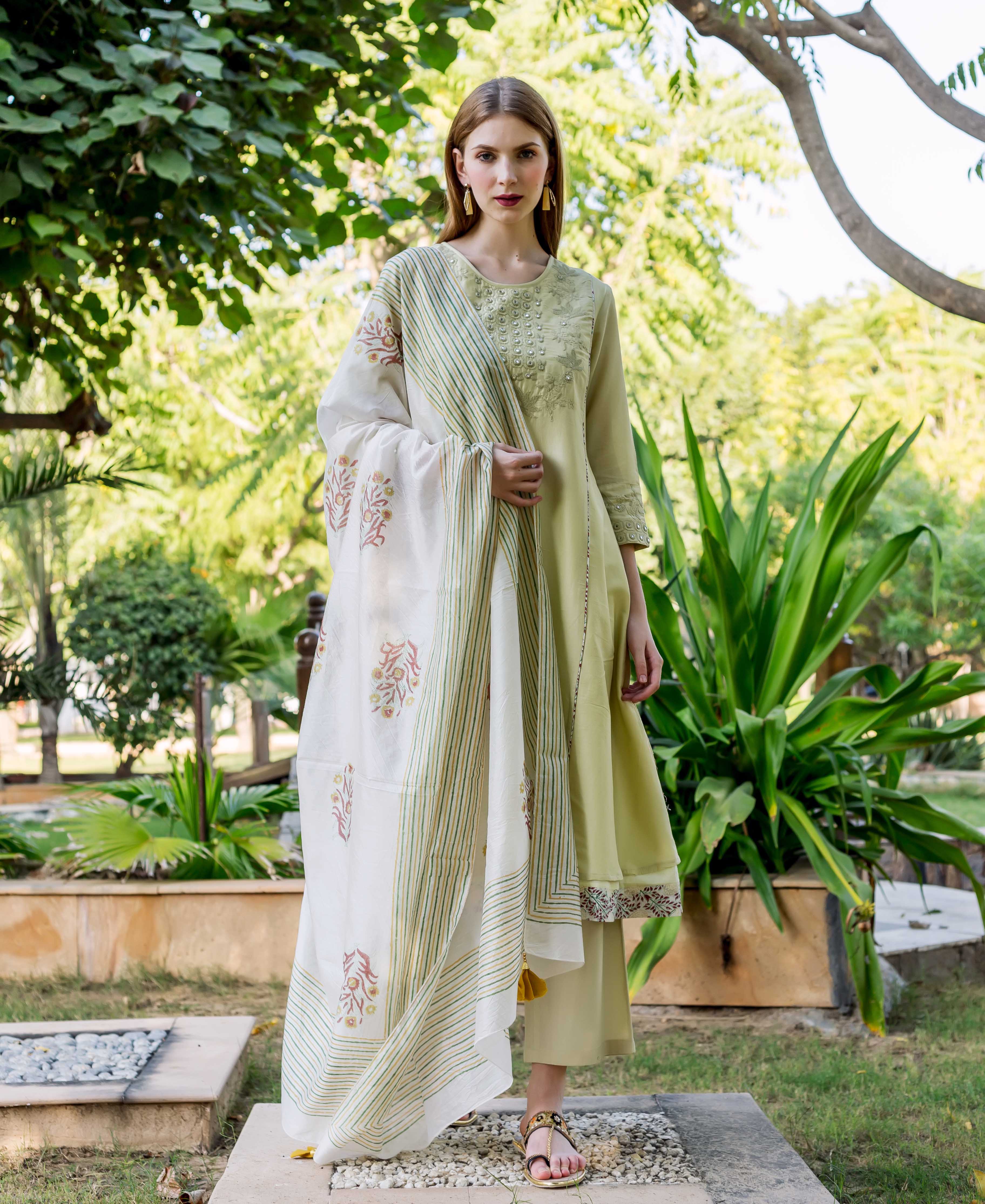 Full-length model in sea green embroidered A-line kurta with printed hem and block-printed dupatta.