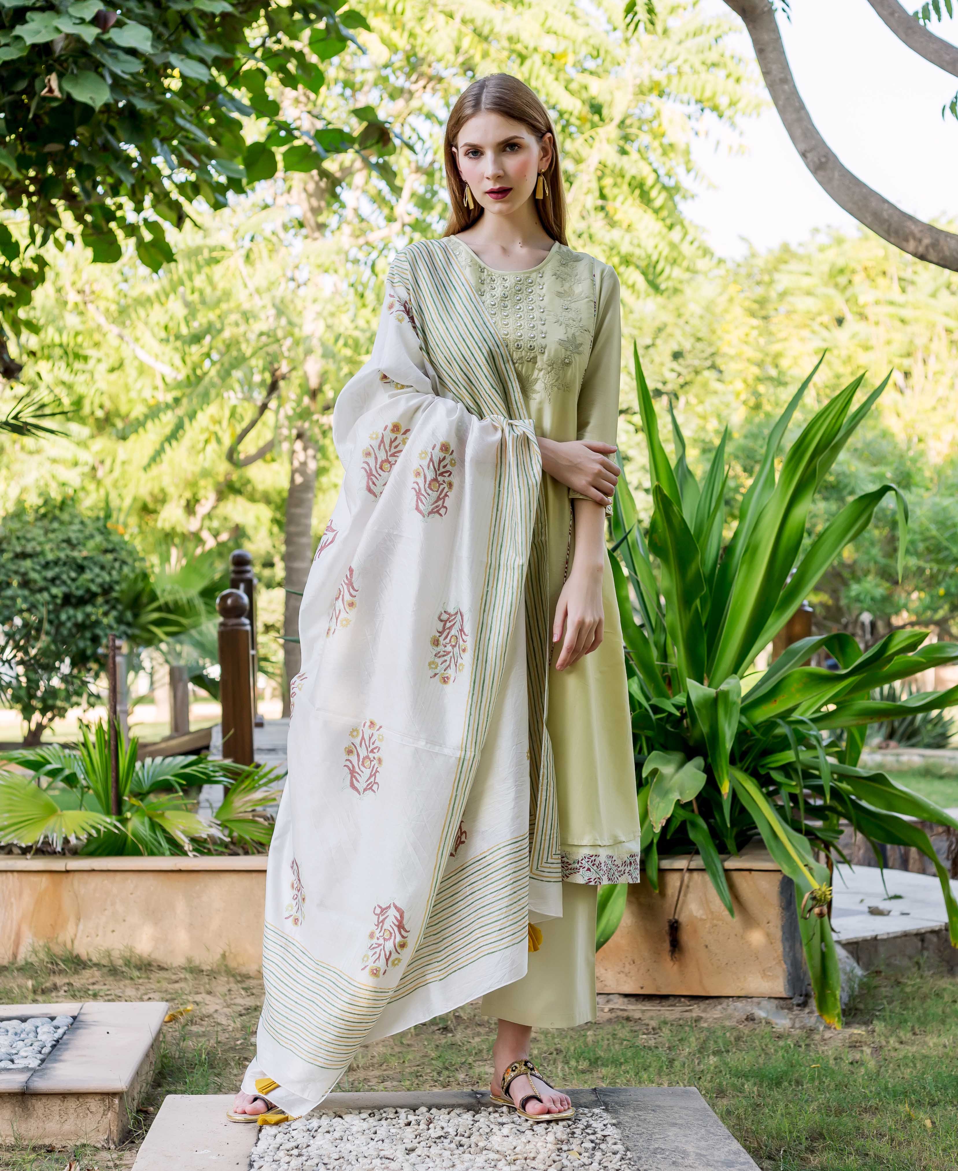 Full-length model in sea green embroidered A-line kurta with printed hem and floral dupatta.