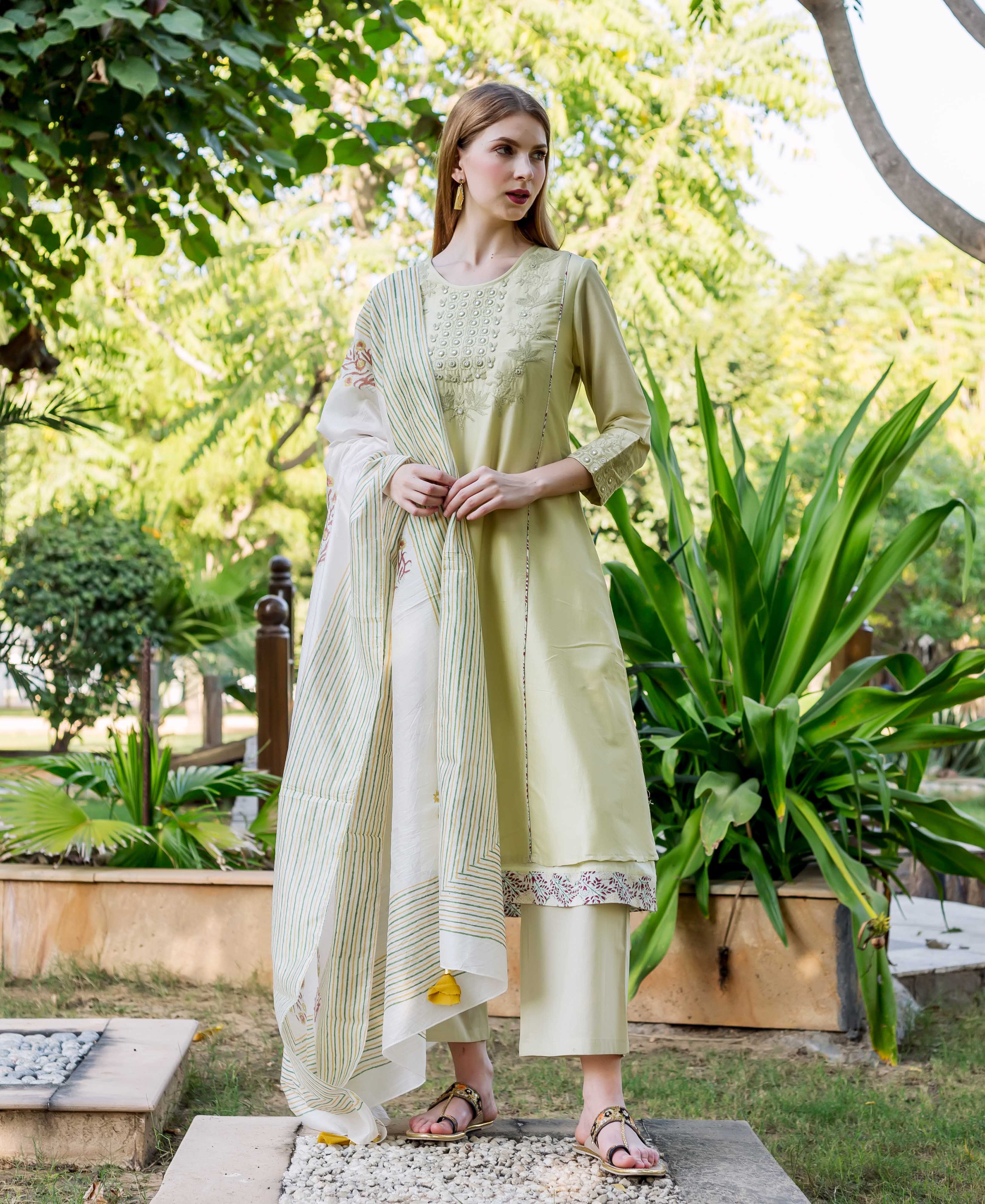 Model in sea green embroidered A-line kurta with a floral printed hem.