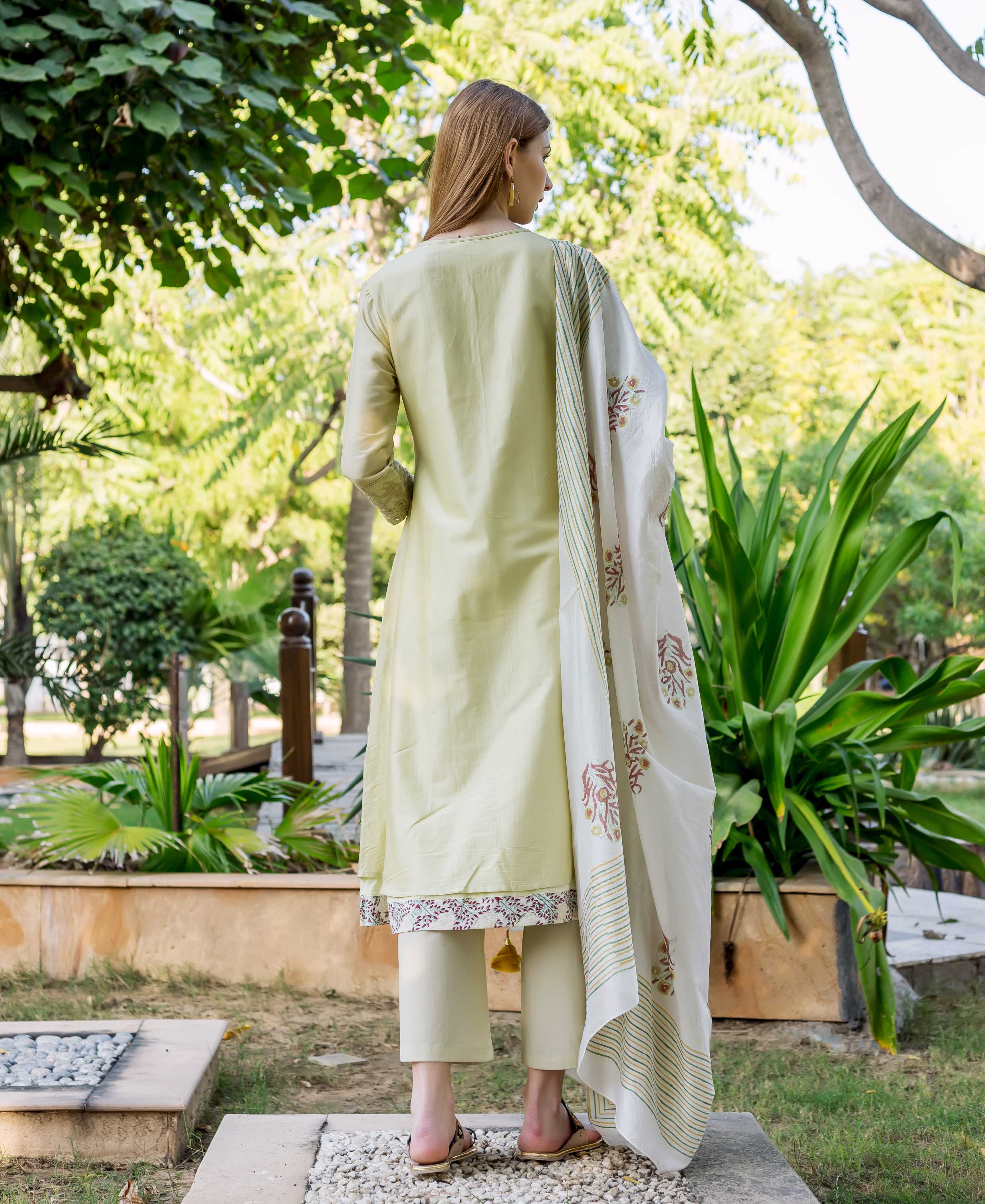 Rear view of model in sea green embroidered A-line kurta with printed hem.