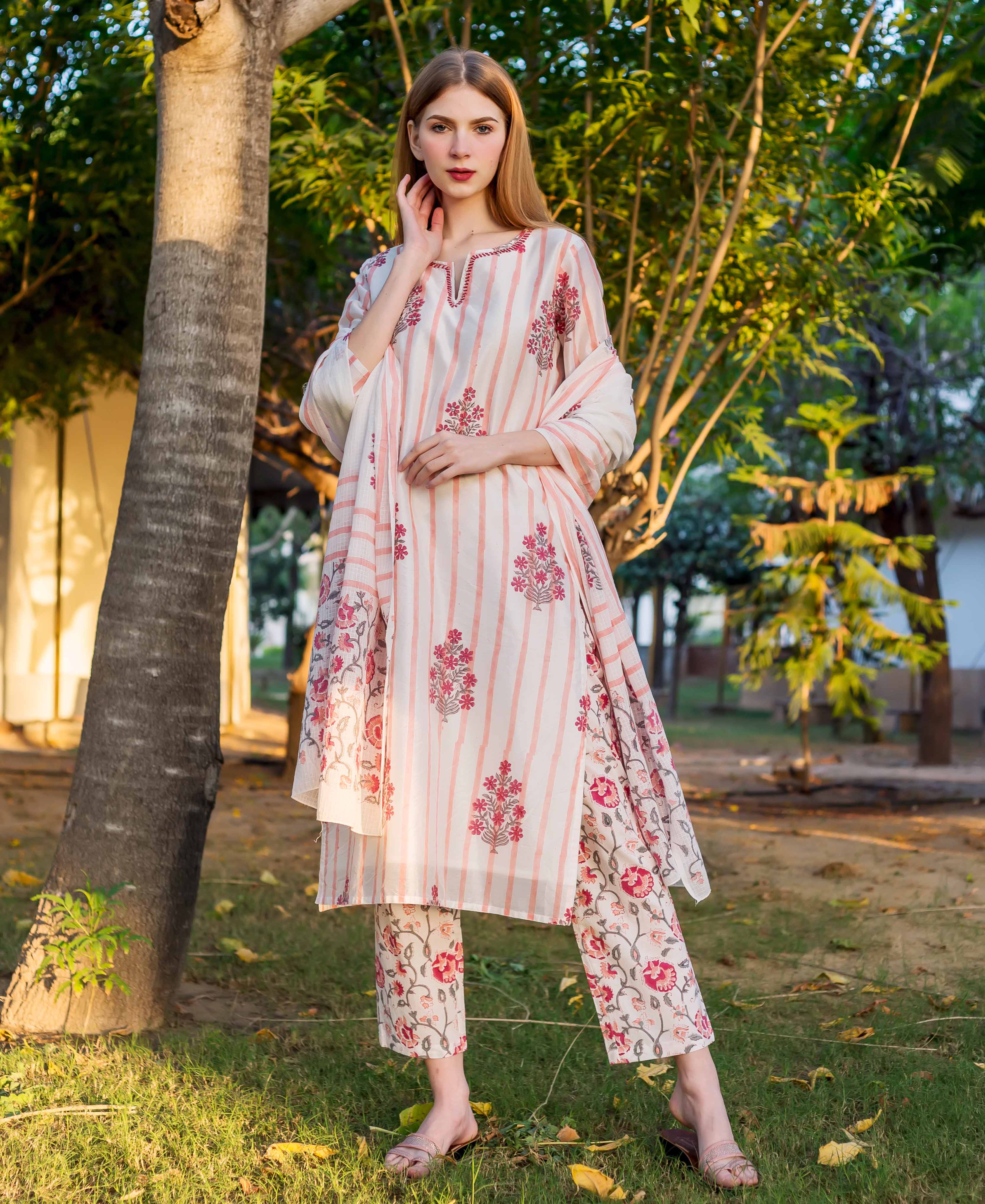 Woman in an outdoor setting wearing a white and pink striped and floral printed kurta set.