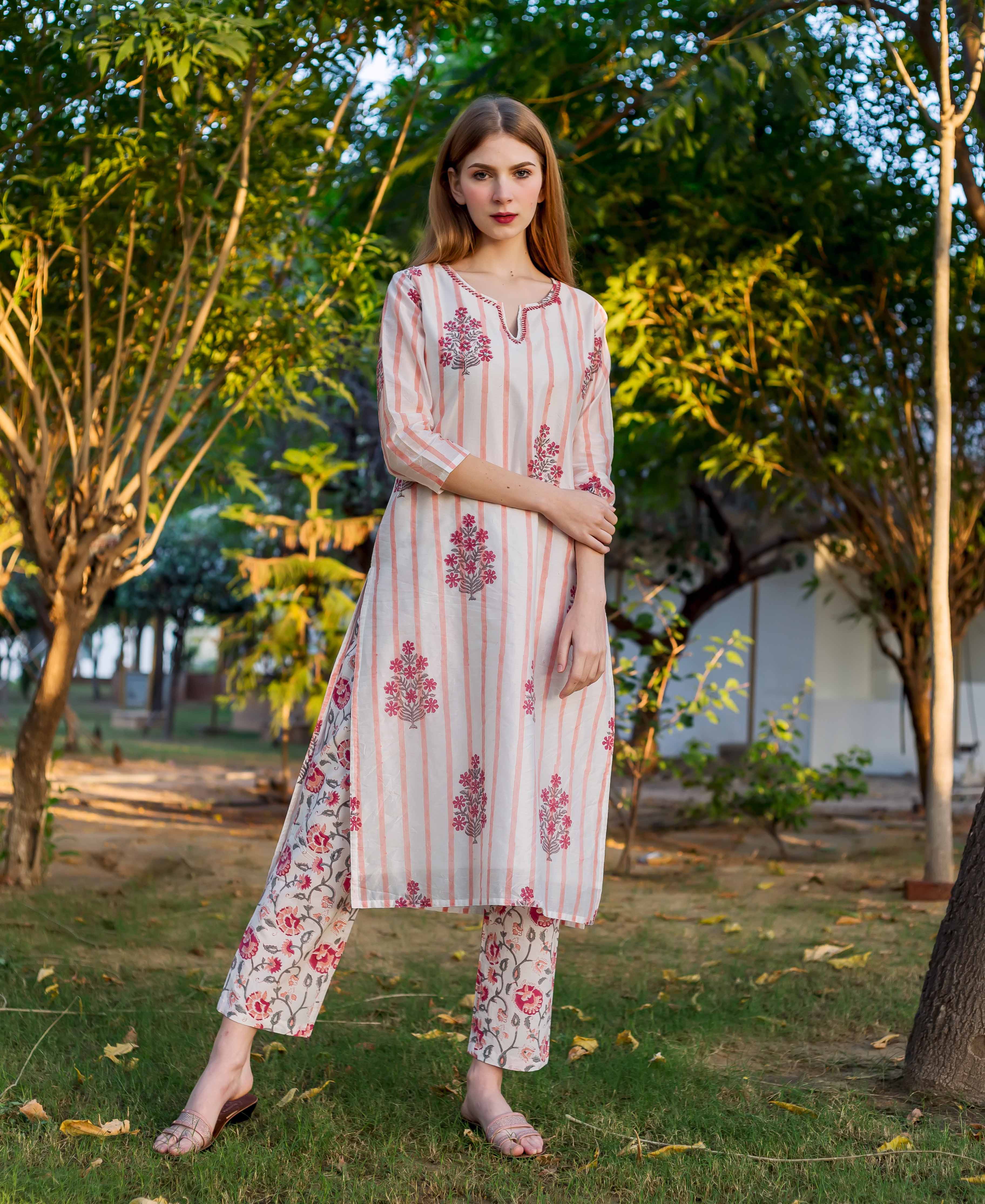 Woman wearing white and pink striped kurta with pink flowers and matching floral pants.