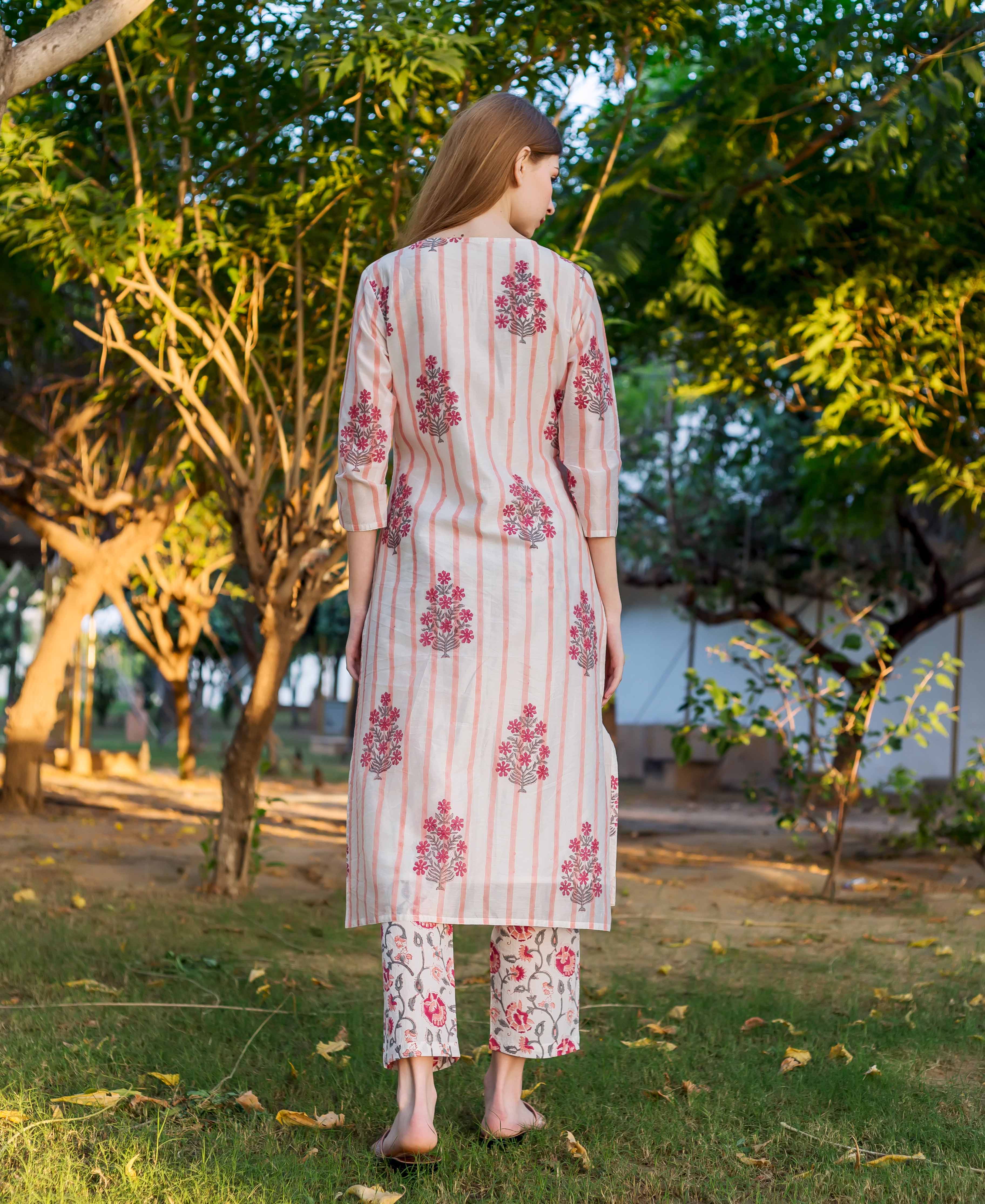 Woman from behind in off-white kurta, pink stripes and floral block print, and matching pants.