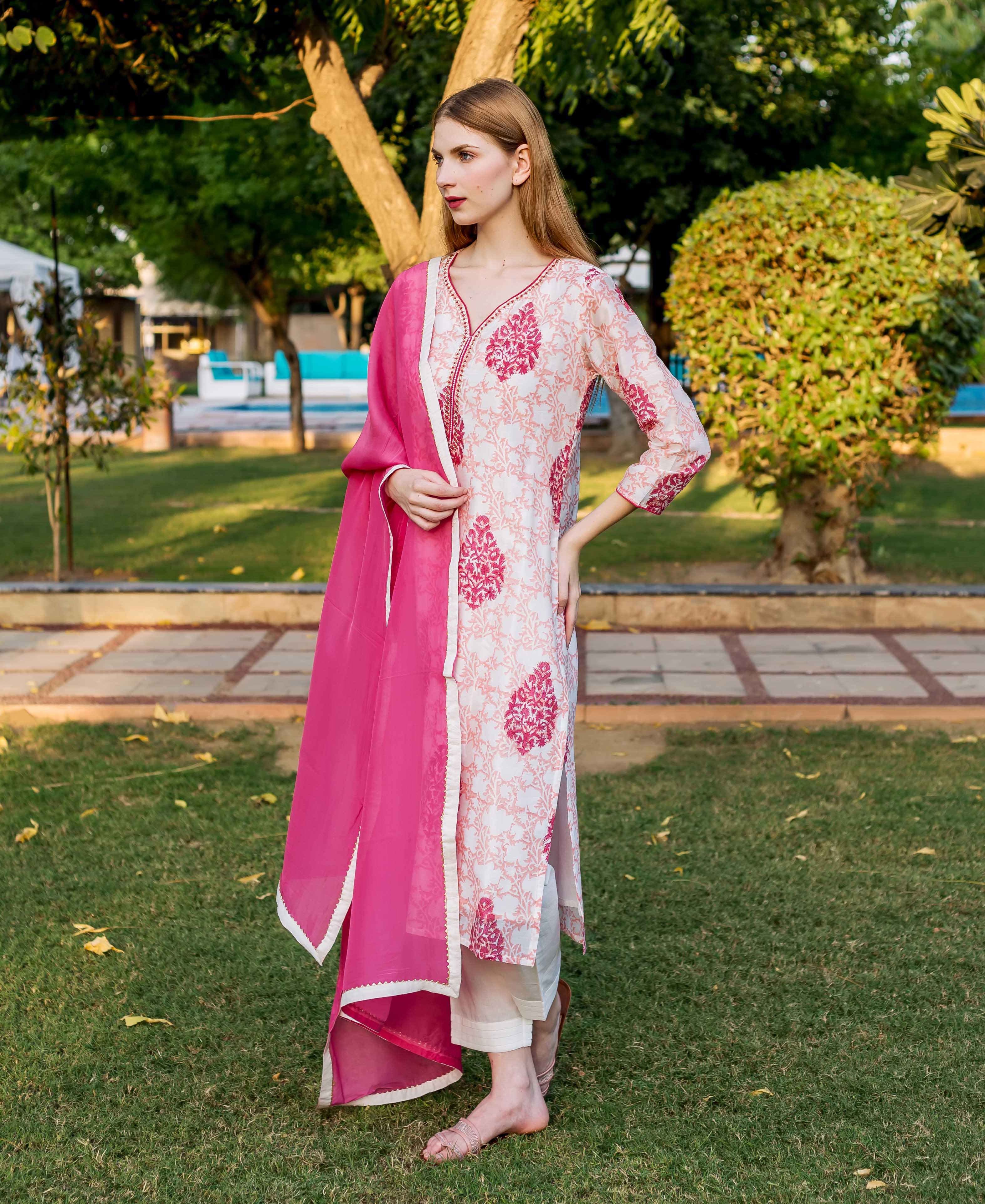 Side view of model in peach and pink block printed kurta and bright pink dupatta.