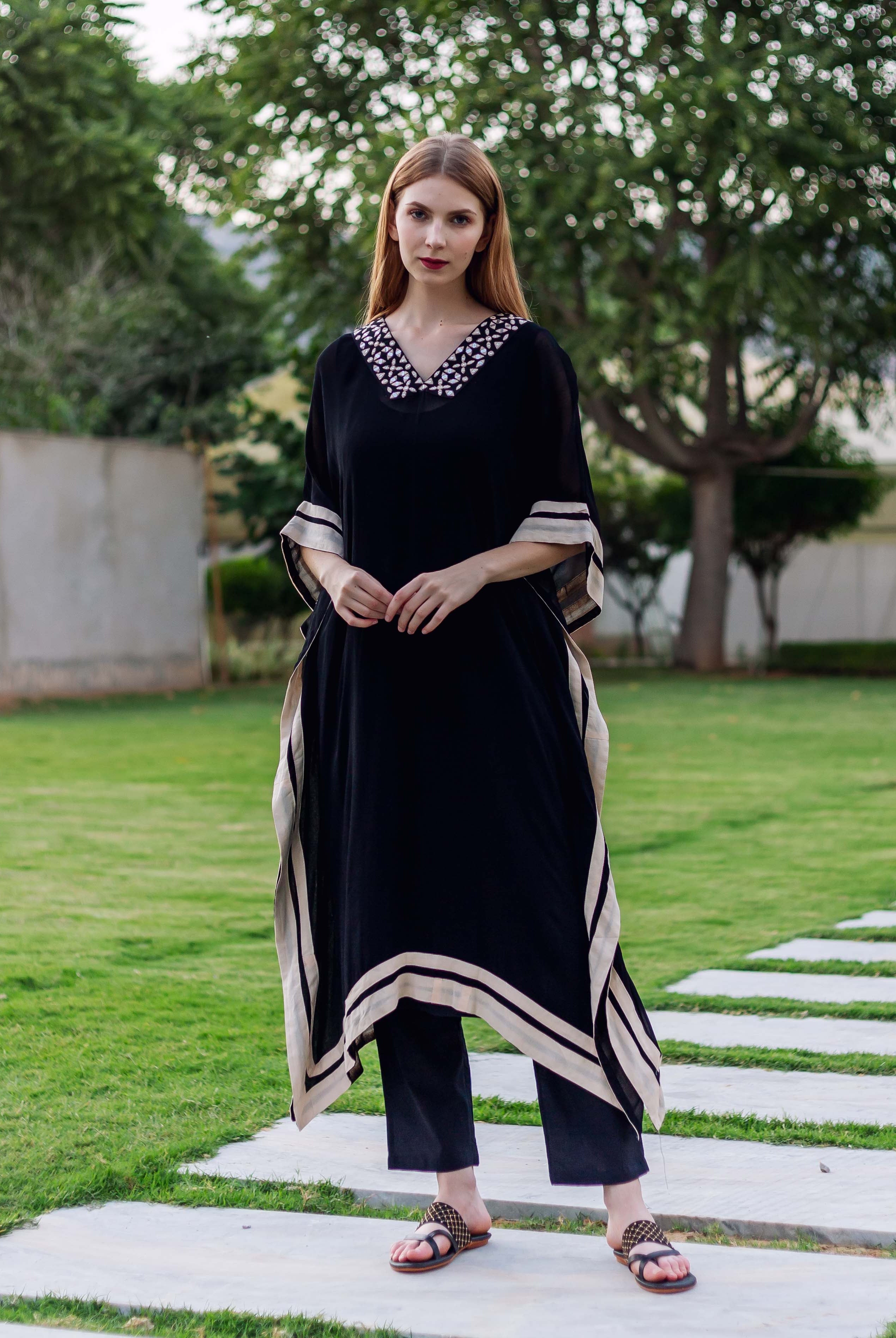 A model wearing a black kaftan with white embroidery and block-printed borders.