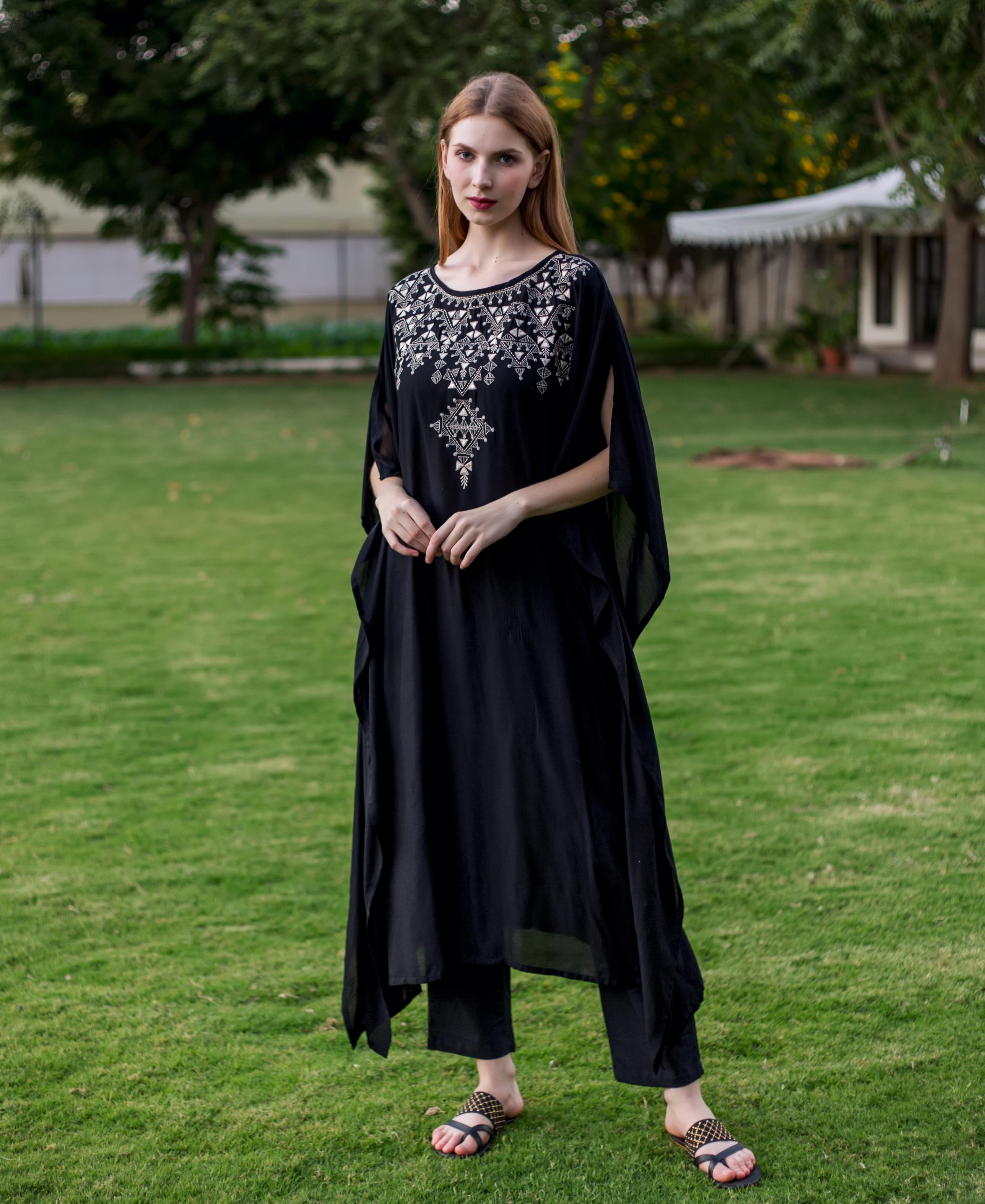 Front view of a model in a black muslin kaftan with intricate white geometric embroidery.