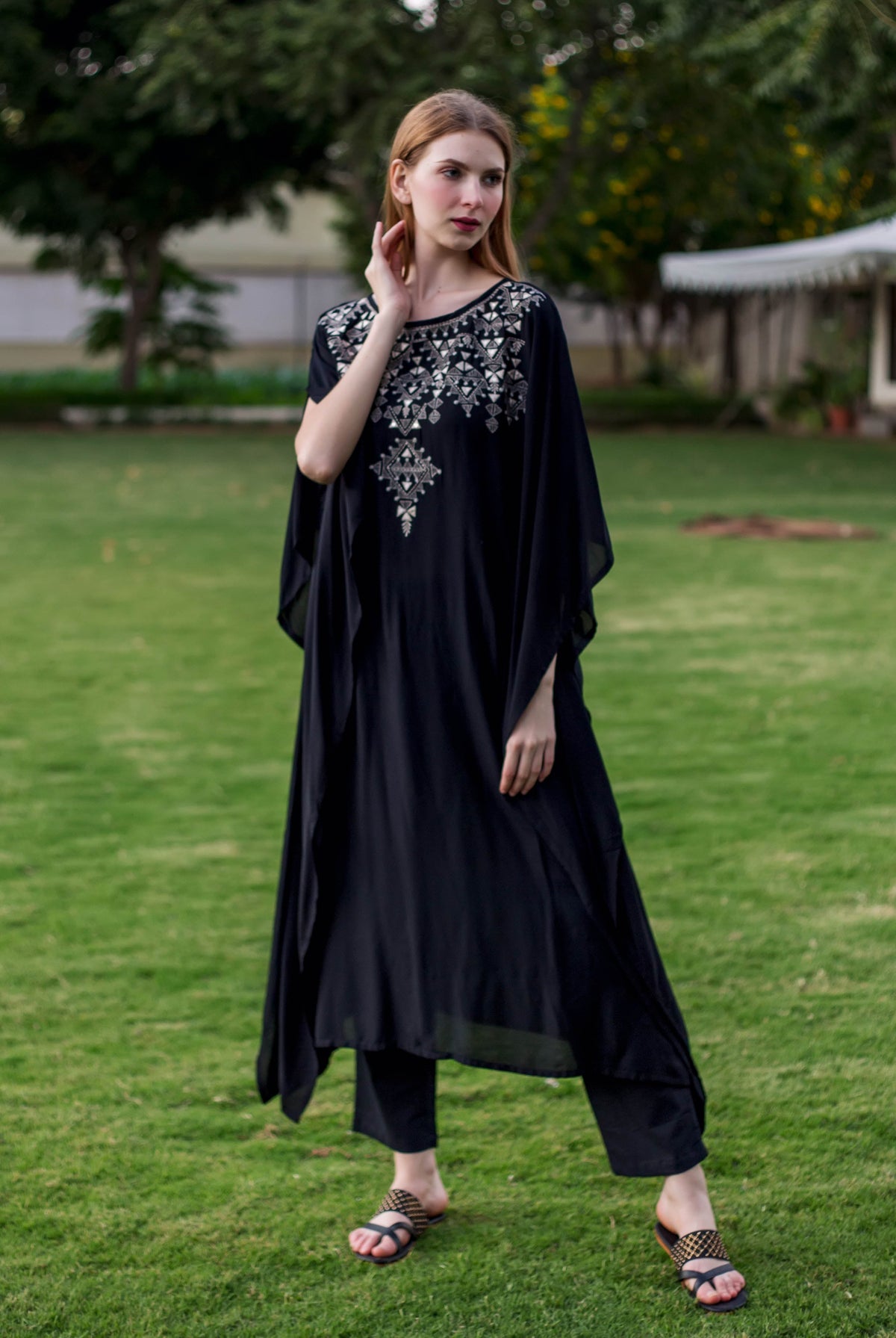 Full front view of model in black muslin kaftan with silver geometric embroidery and pants.