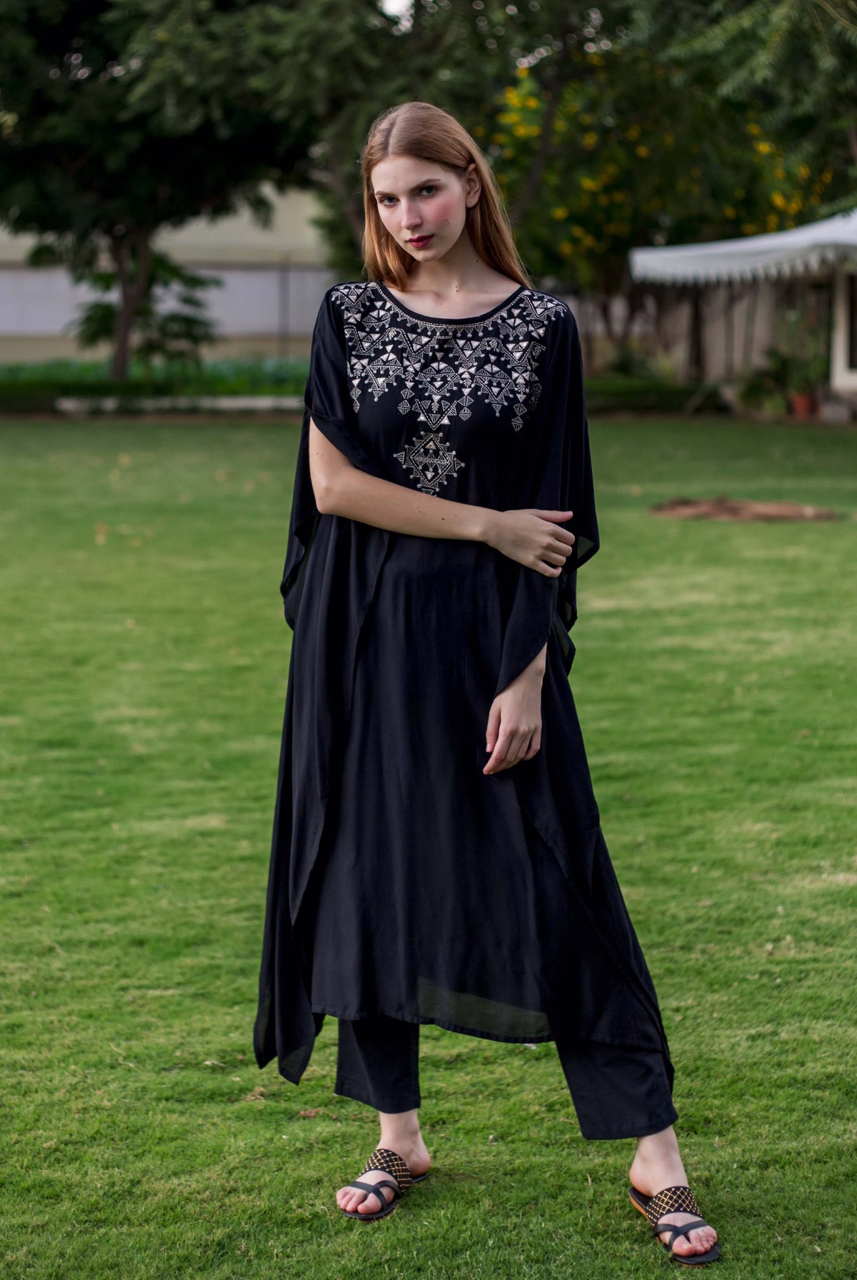 Model in black kaftan with intricate silver geometric embroidery and matching pants.