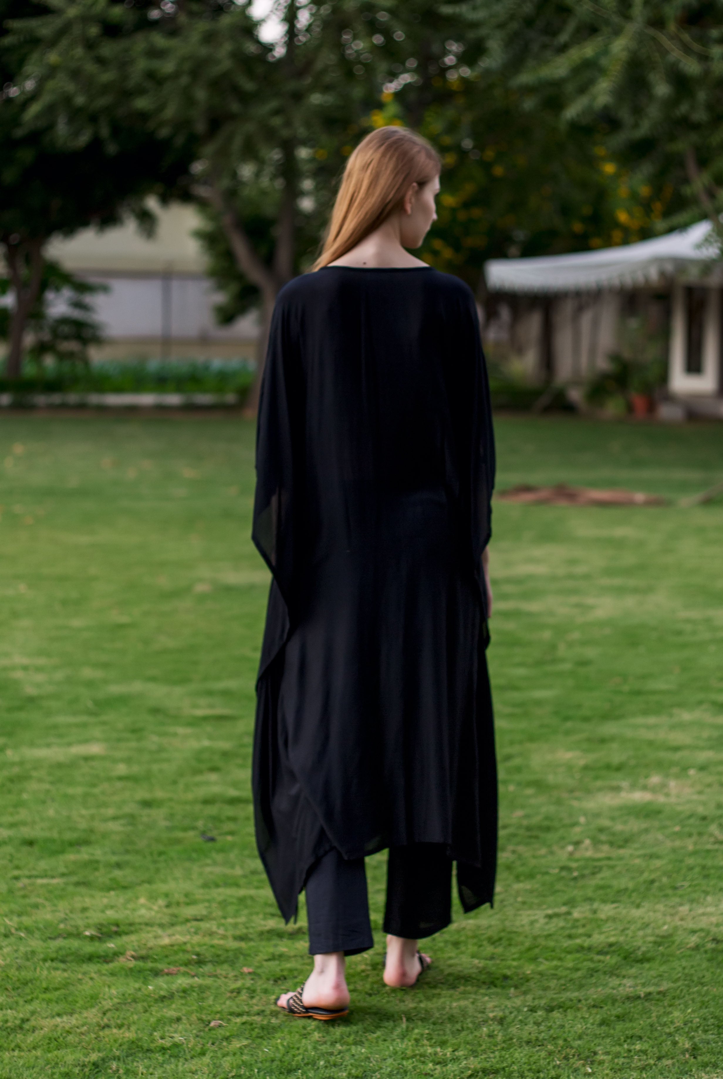 A model wearing a black, long-sleeved kaftan with an embroidered design on the front.