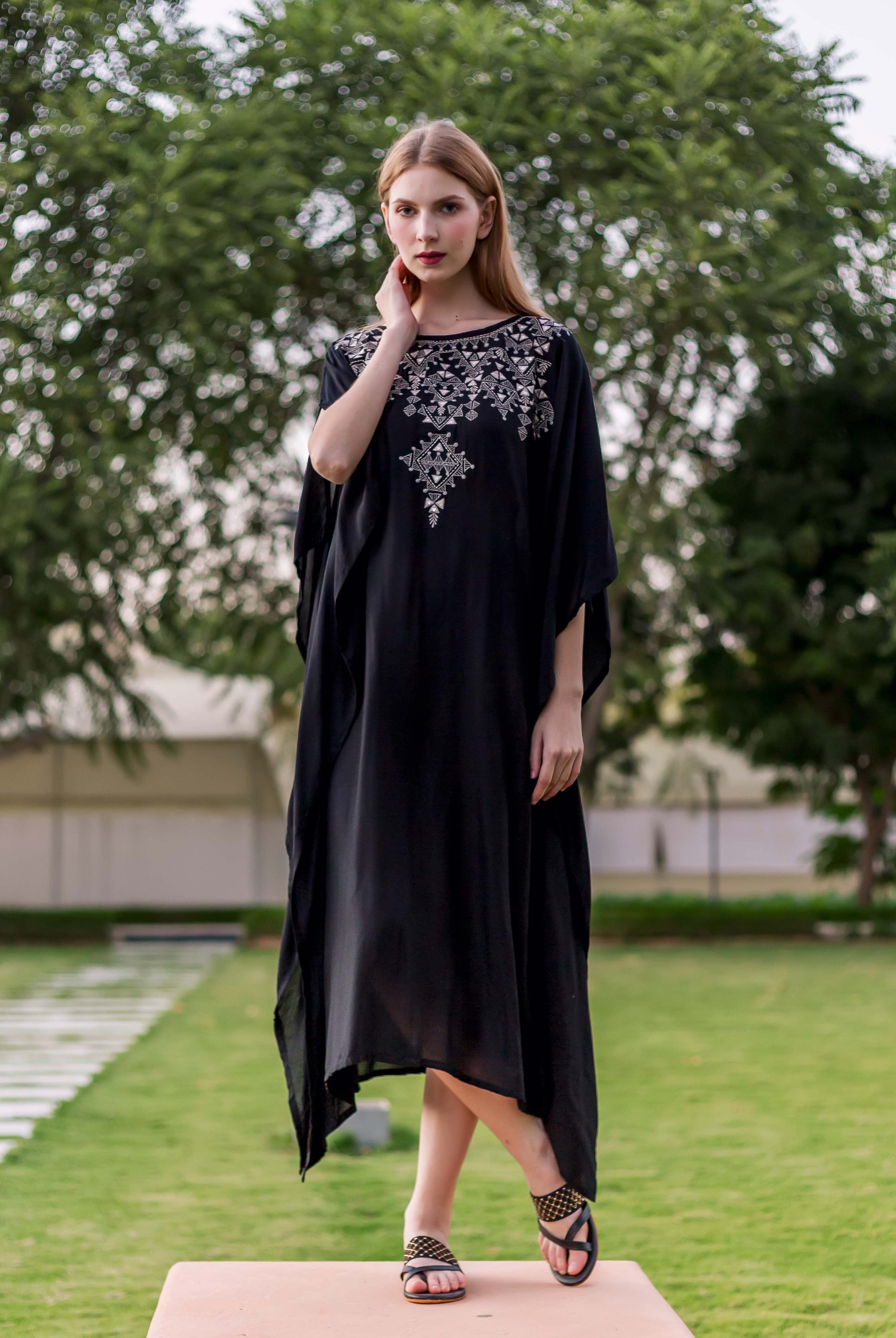 Full-length front view of model in black kaftan with intricate white ethnic embroidery.
