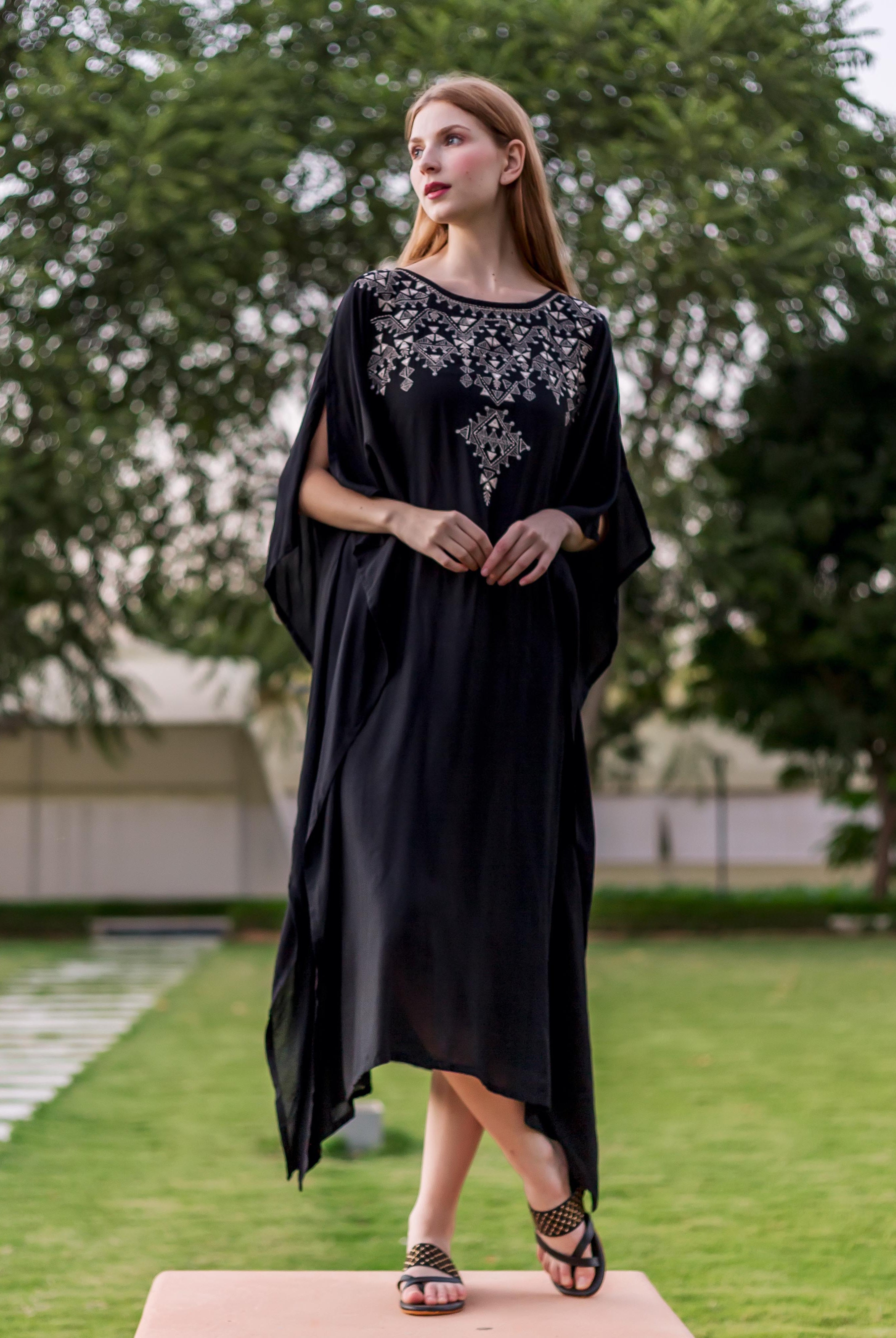 Front view of model wearing a black kaftan with intricate silver ethnic embroidery on the yoke.