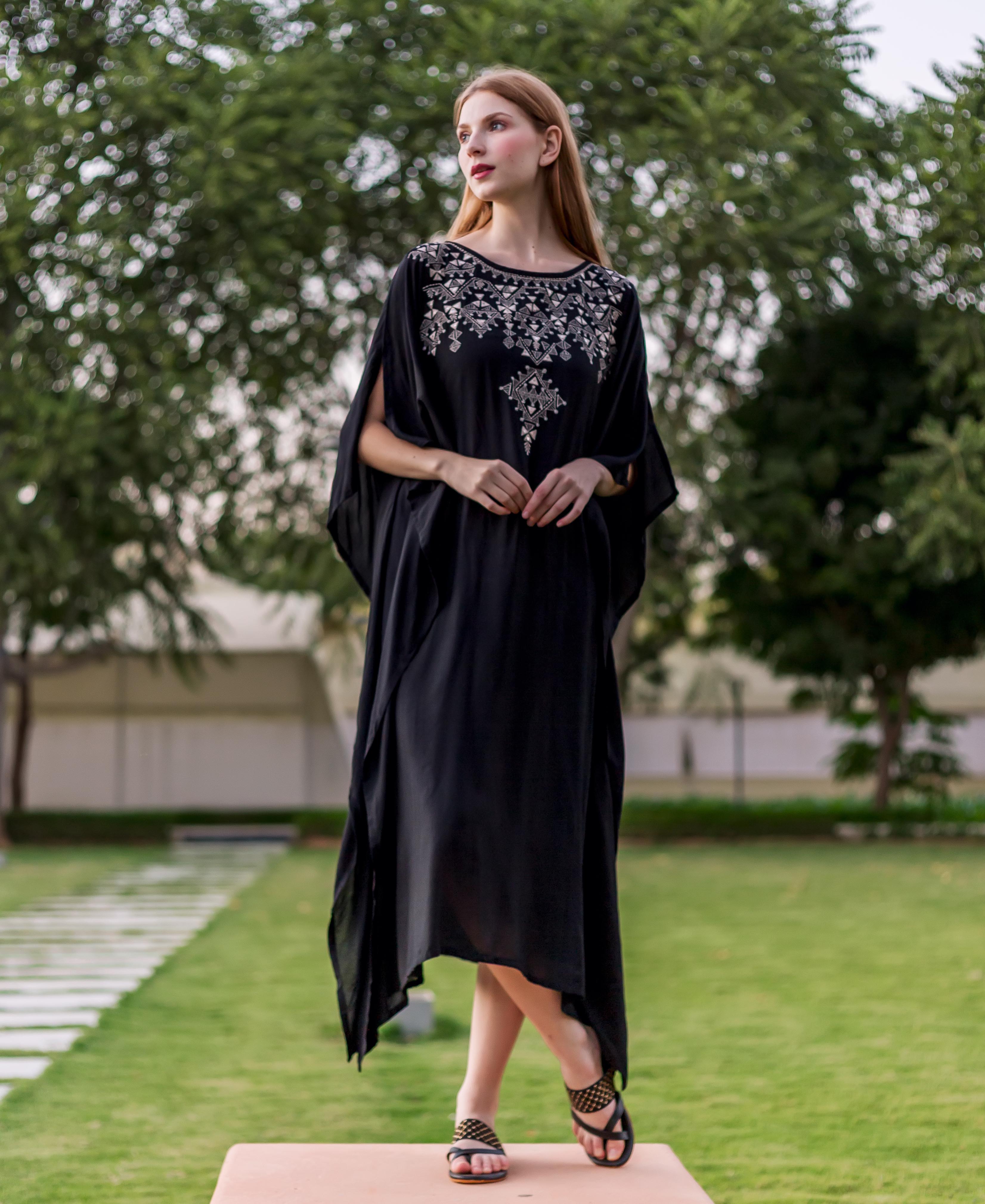 Front view of model wearing a black kaftan with intricate silver ethnic embroidery on the yoke.