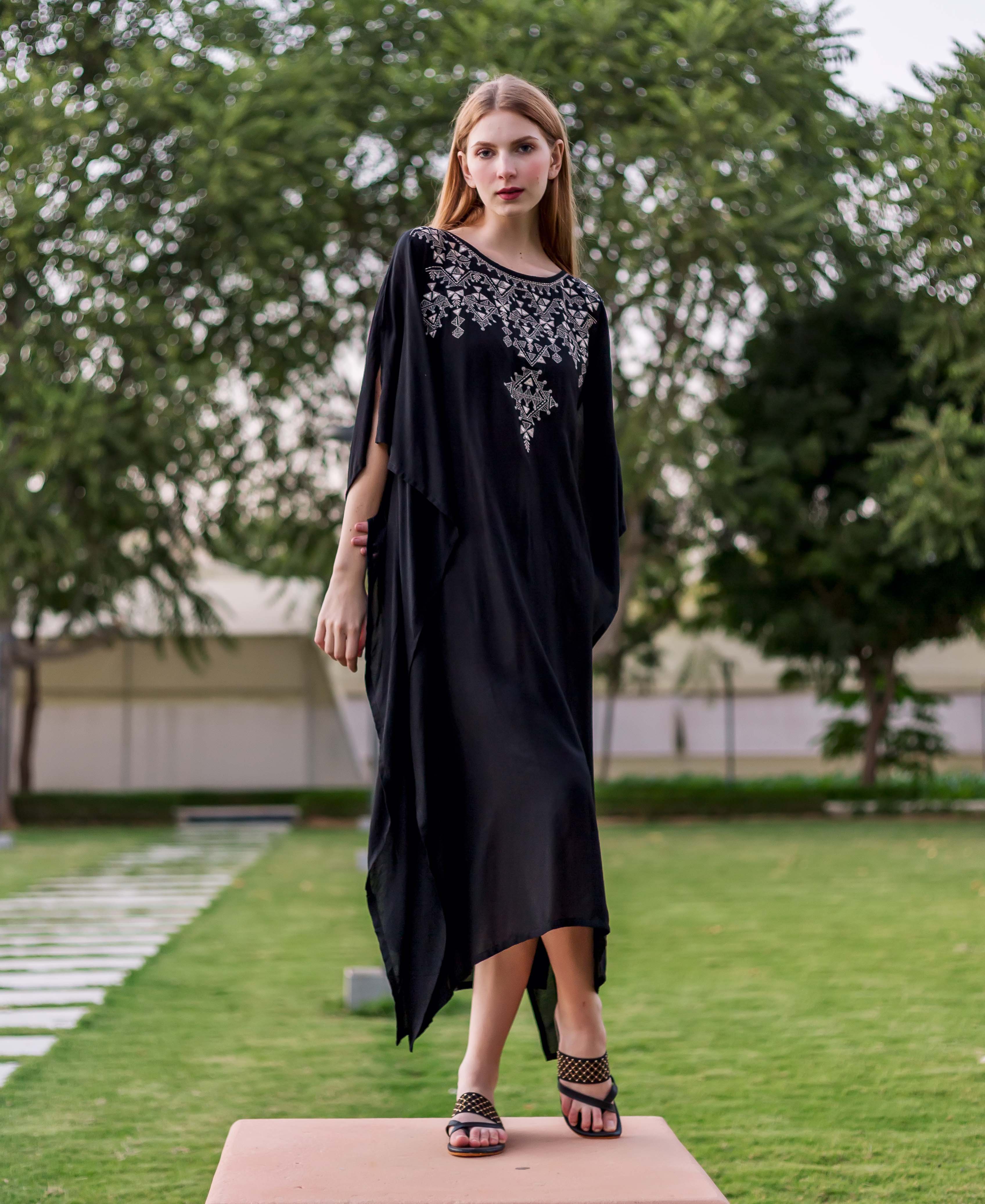 Front view of model in black kaftan with intricate silver embroidered geometric pattern on yoke.